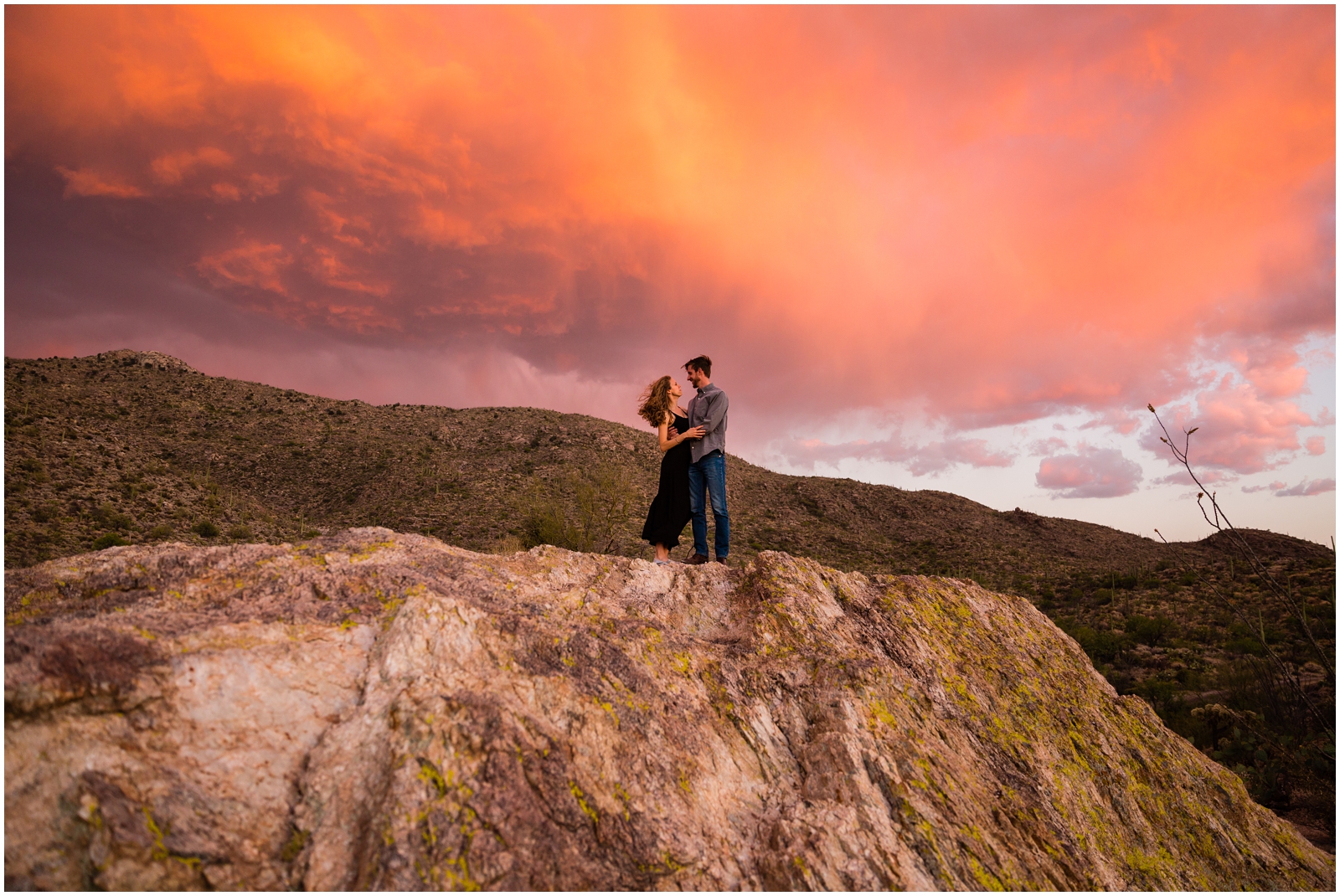 A super colorful sunset happening behind this couple getting their photos taken in Saguaro National Park by Clarissa of Clarissa Wylde Photography