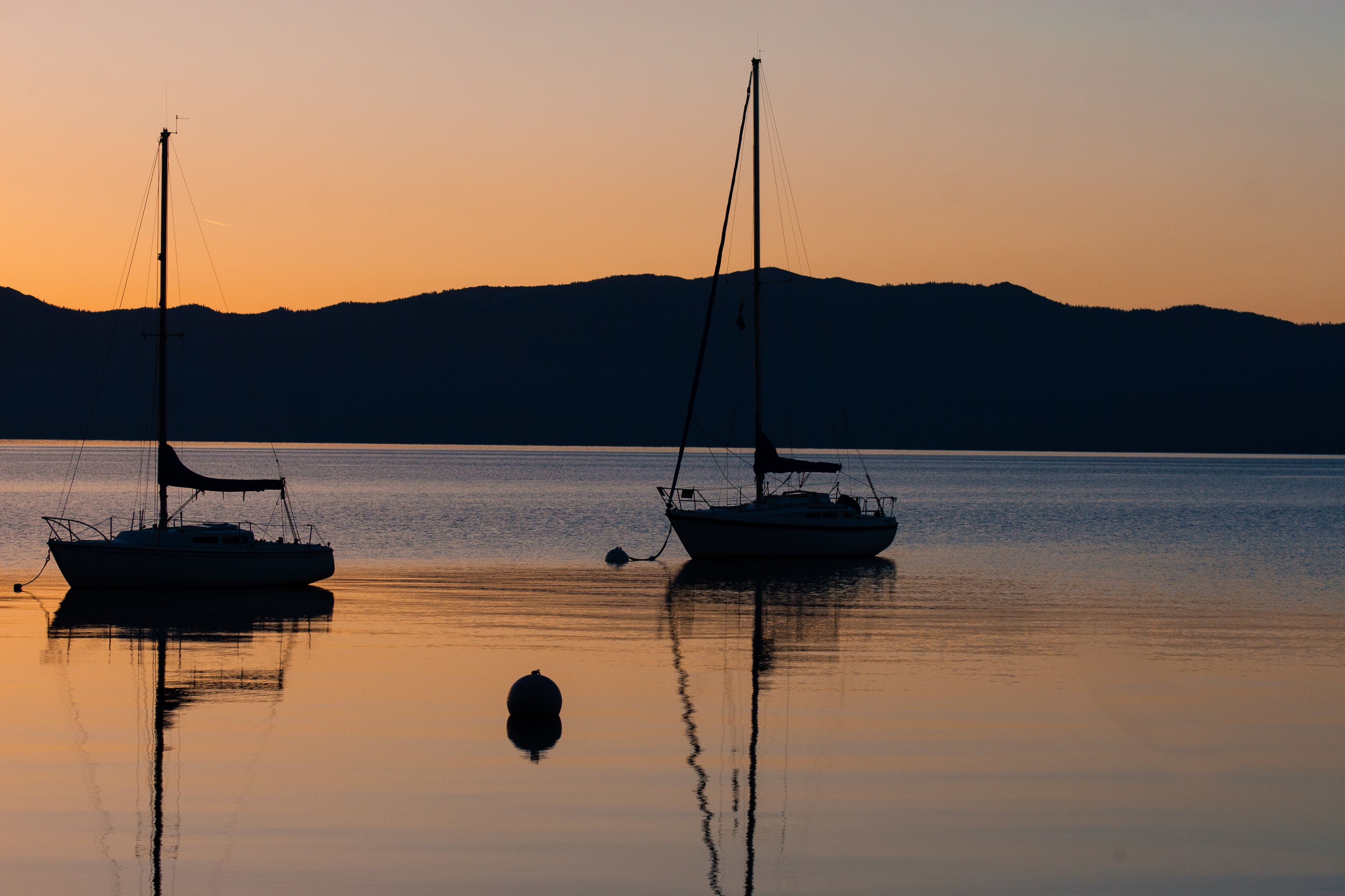 Sail boats moored on Lake Tahoe as the sun rises.