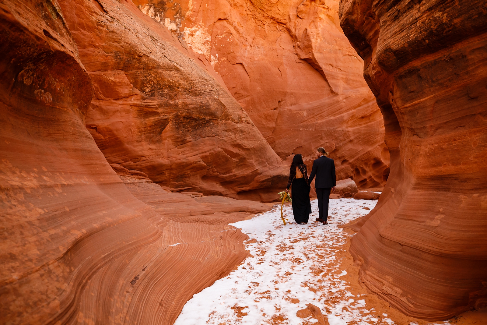 This couple is walking through a snowy slot canyon on their anniversary.