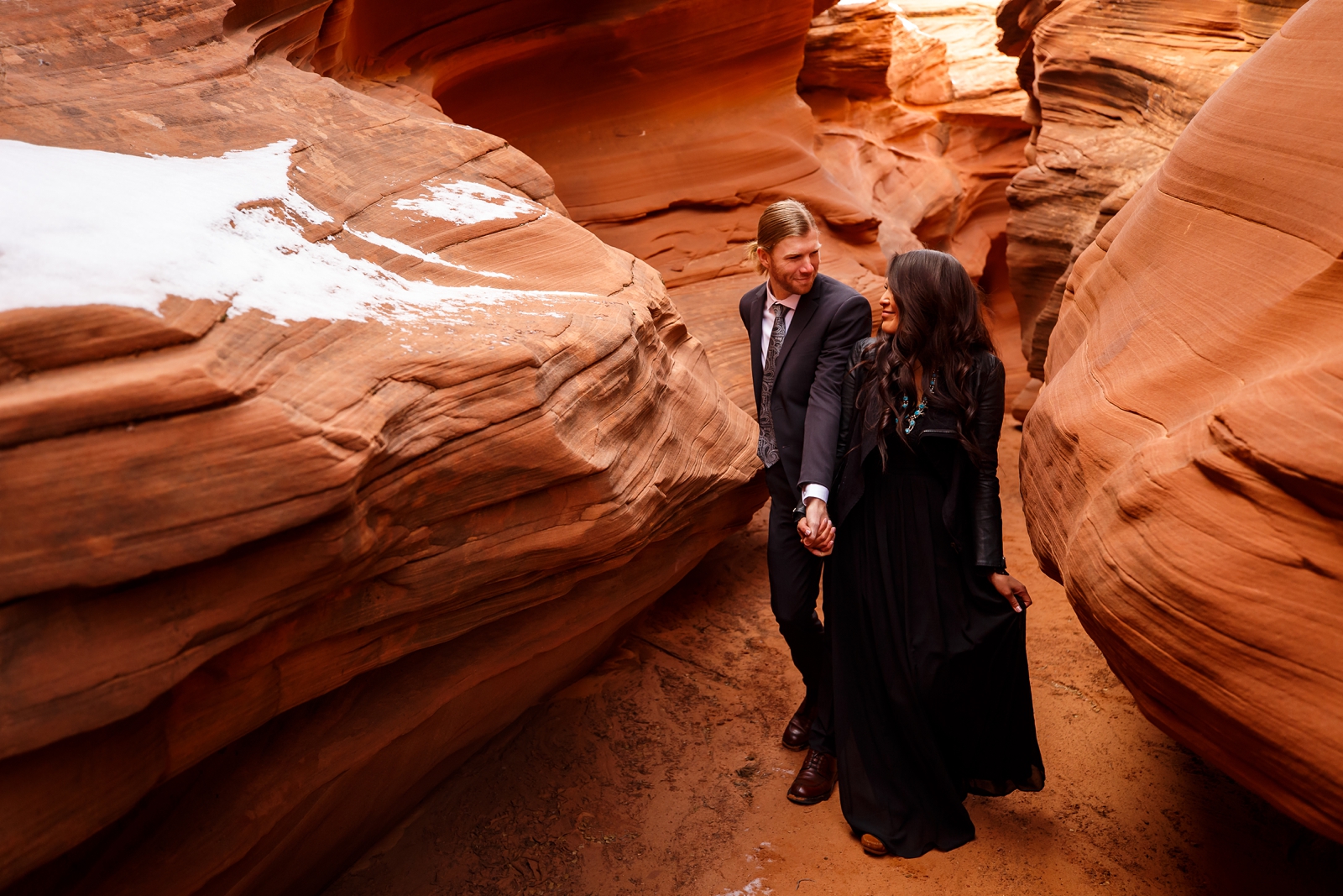Wedding couple squeezing through a slot canyon