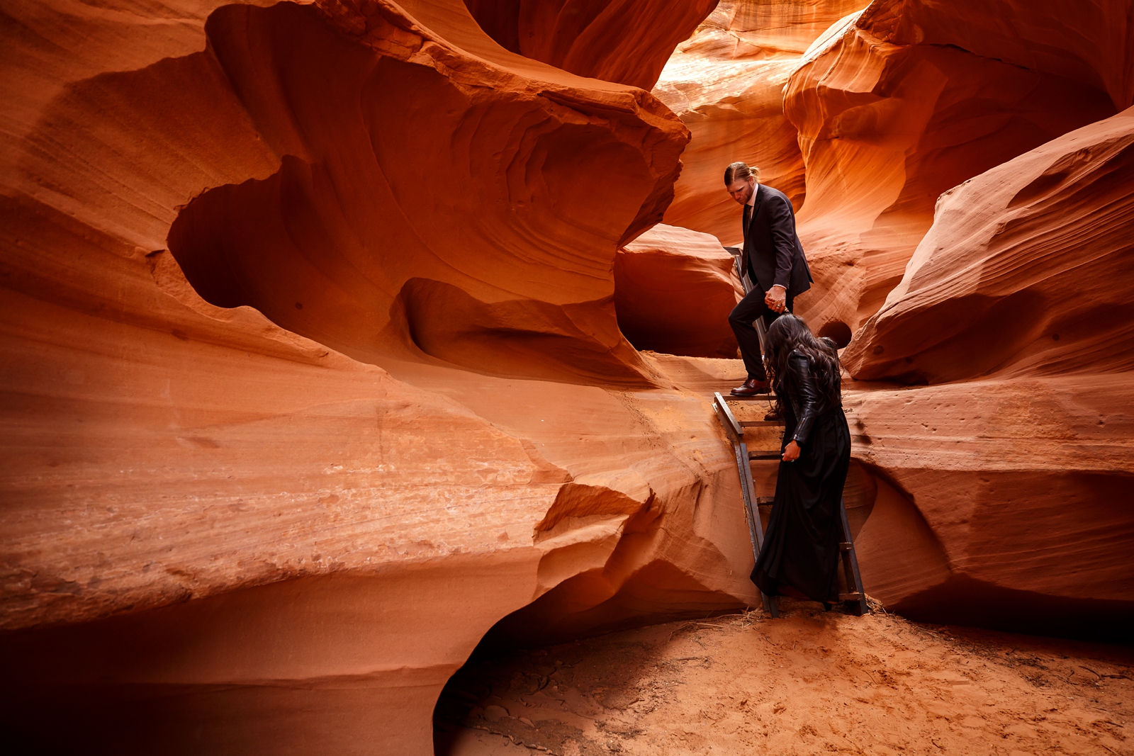Couple climbing ladders in a slot canyon on their anniversary.