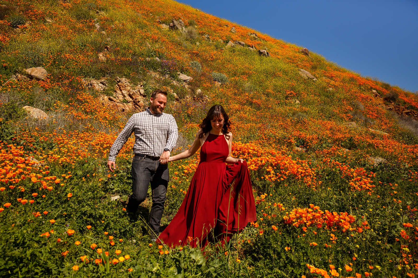 Couple running through wildflowers for their engagement.