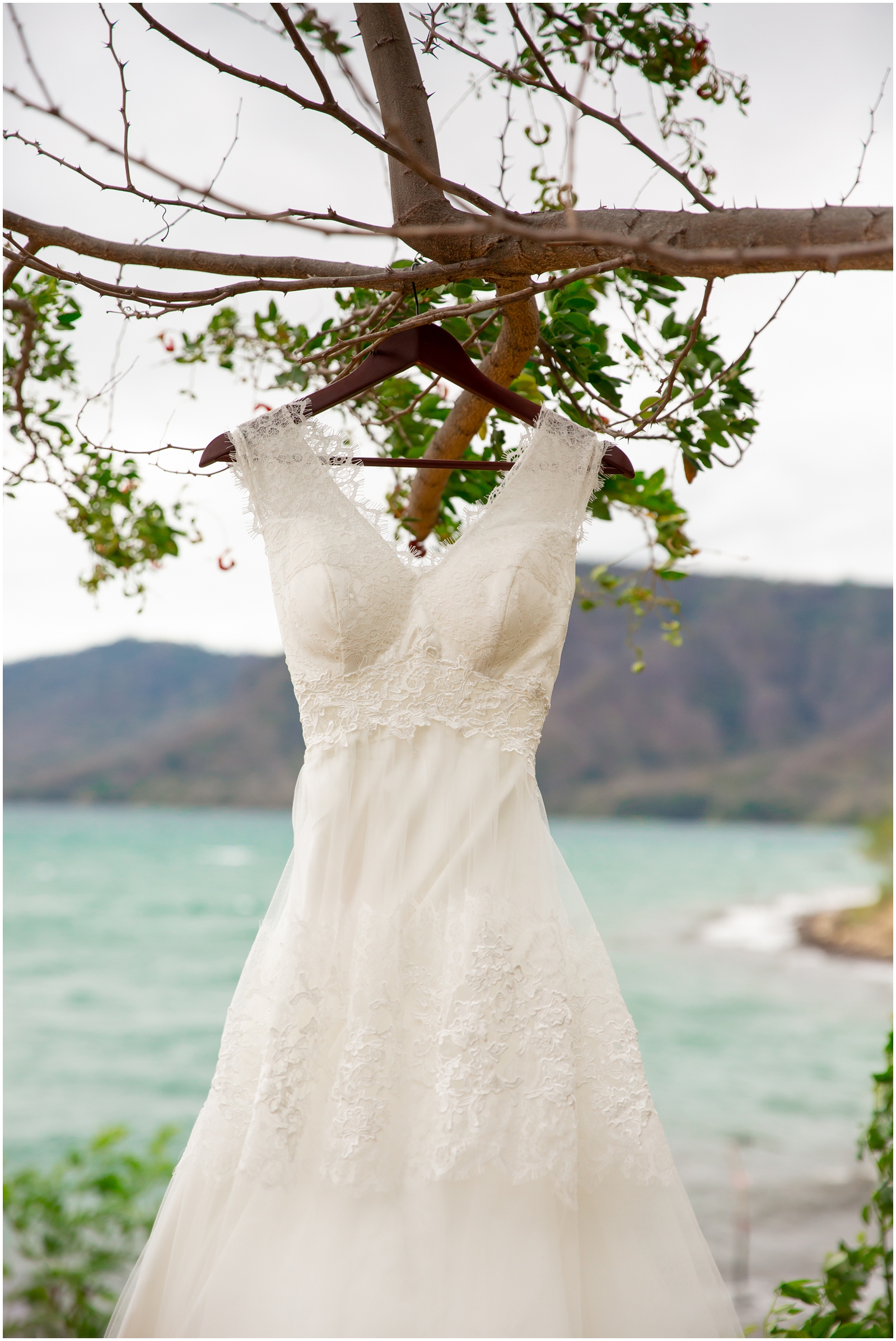 A wedding dress hung outside with a tropical lake in the background.