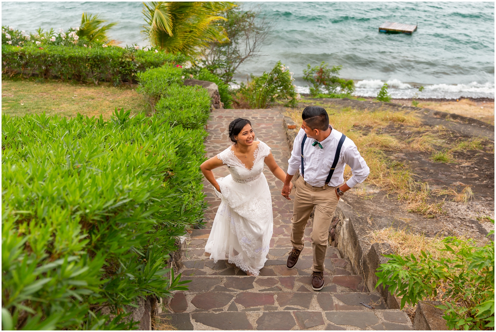 Wedding couple climb lakeside stone staircase after ceremony