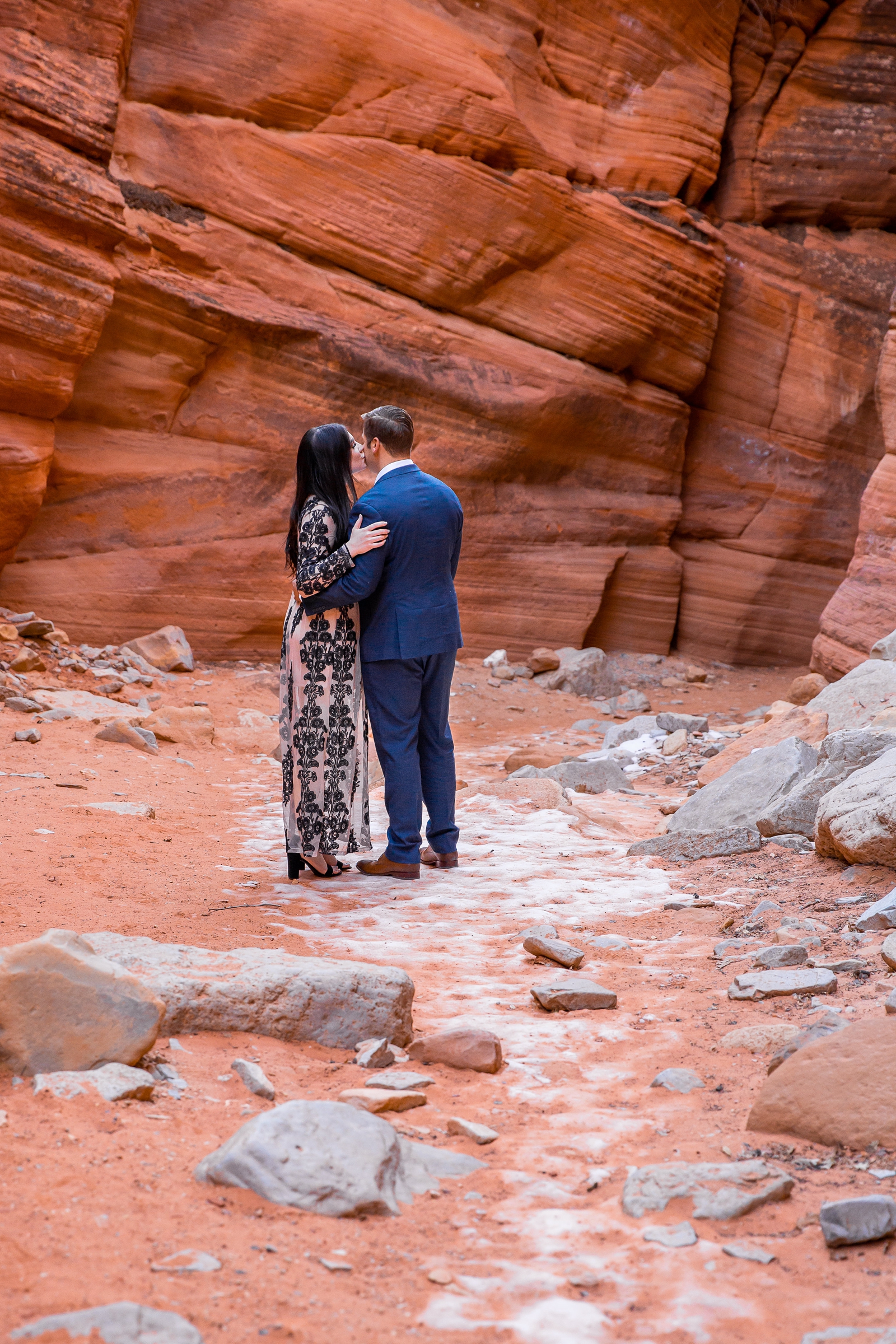 Bride kissing grooms cheek in a slot canyon.