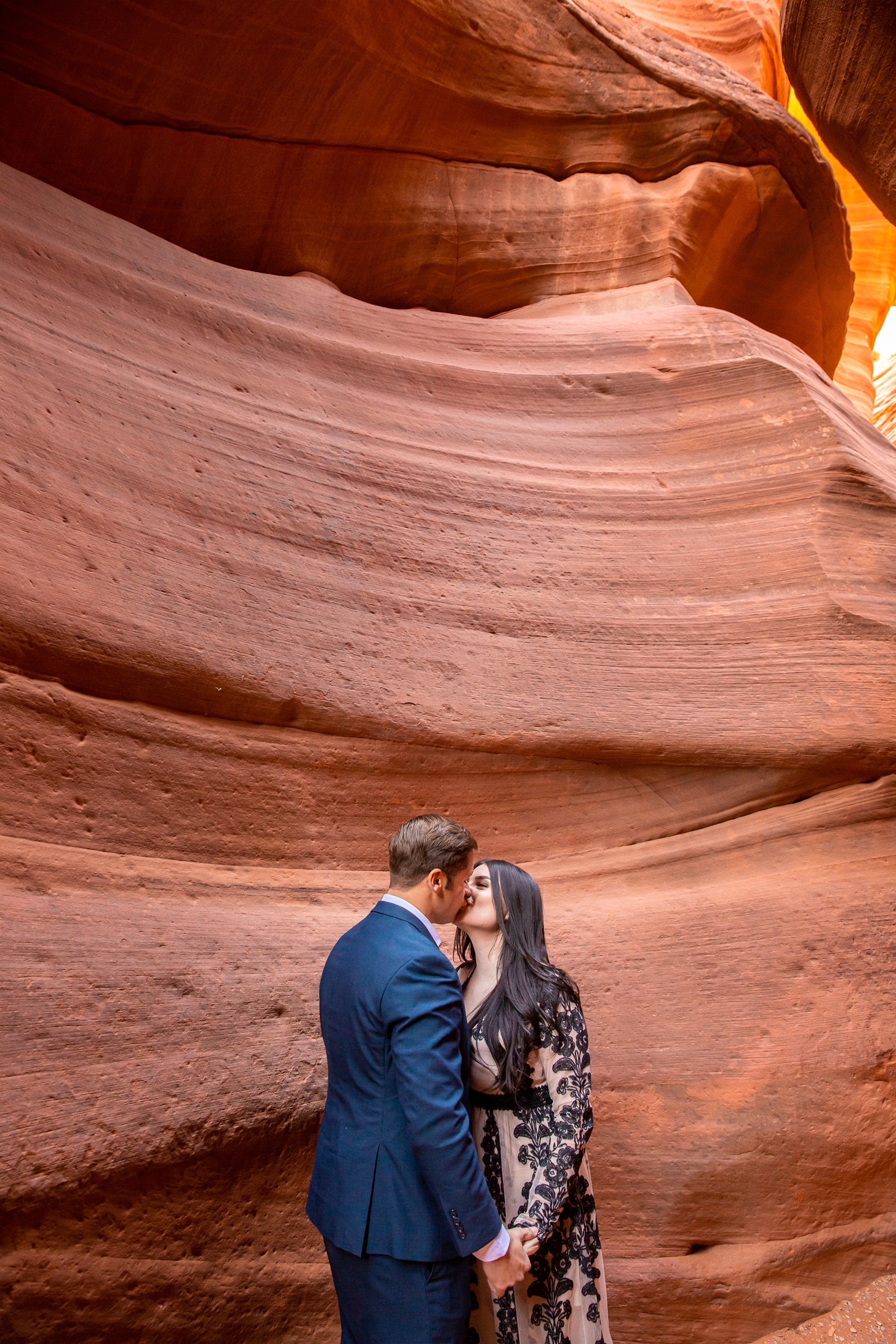 Engaged couple kissing in a red rock slot canyon.