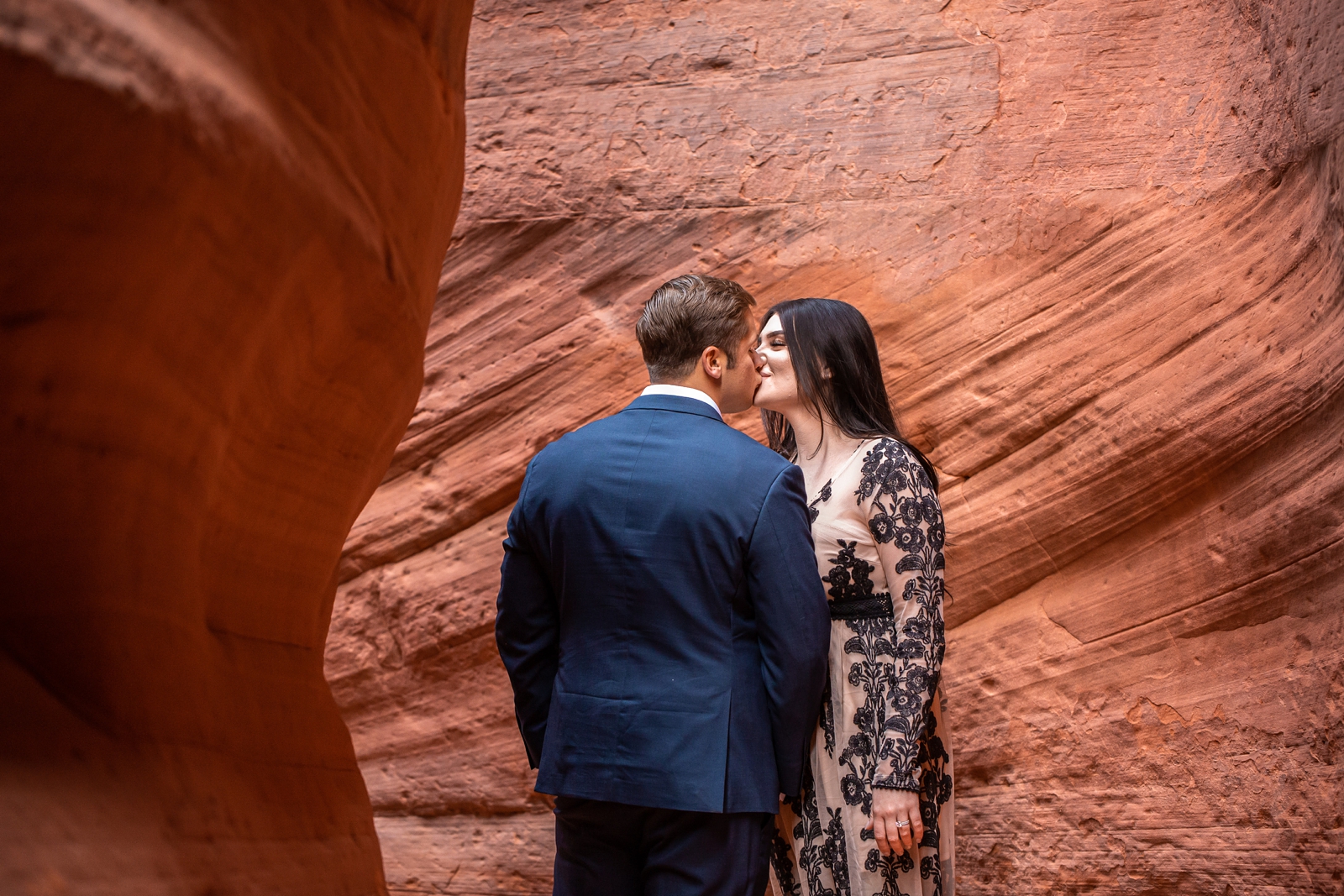 Engaged couple kisses romantically in a slot canyon.
