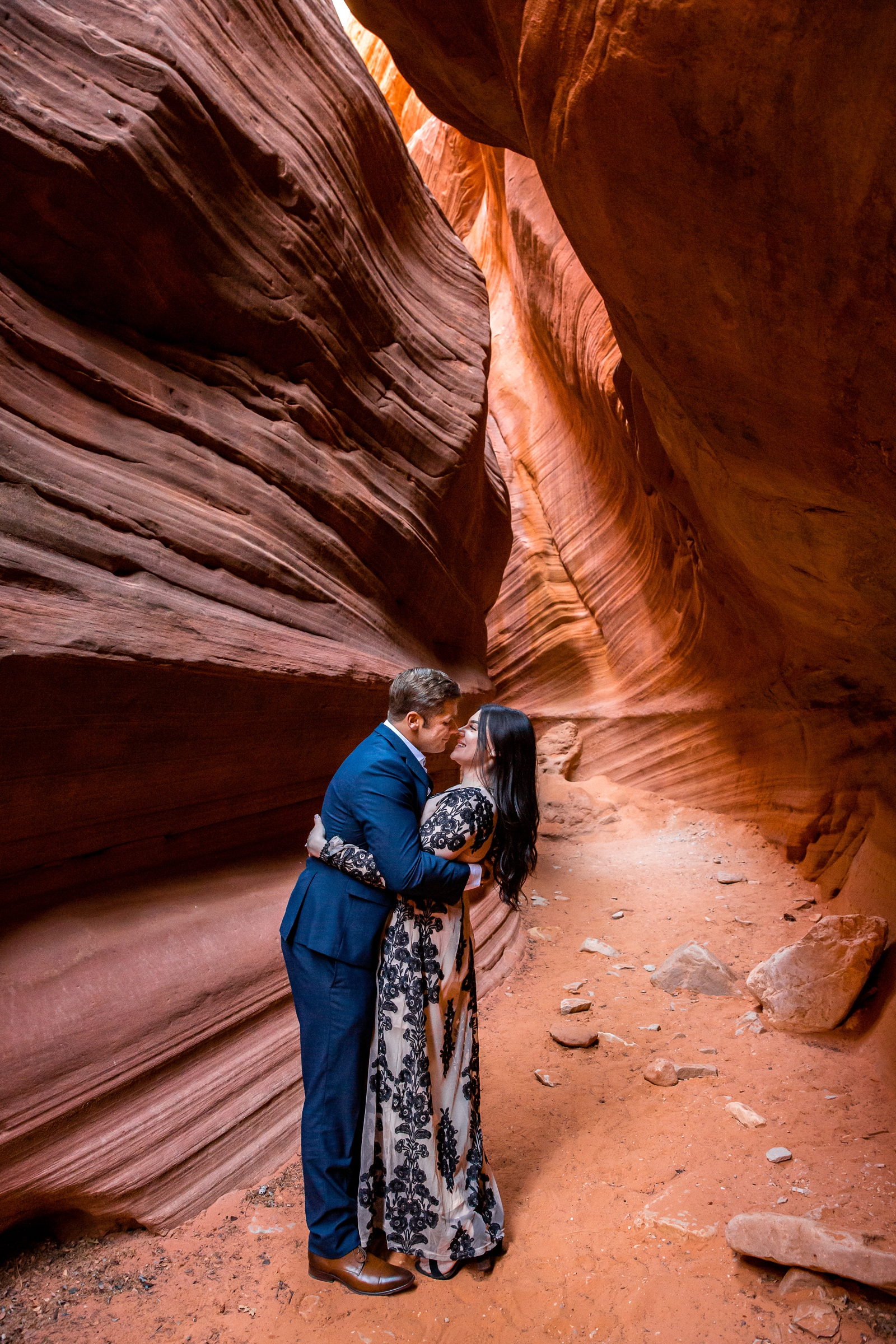Steamy couple almost kissing in a slot canyon.