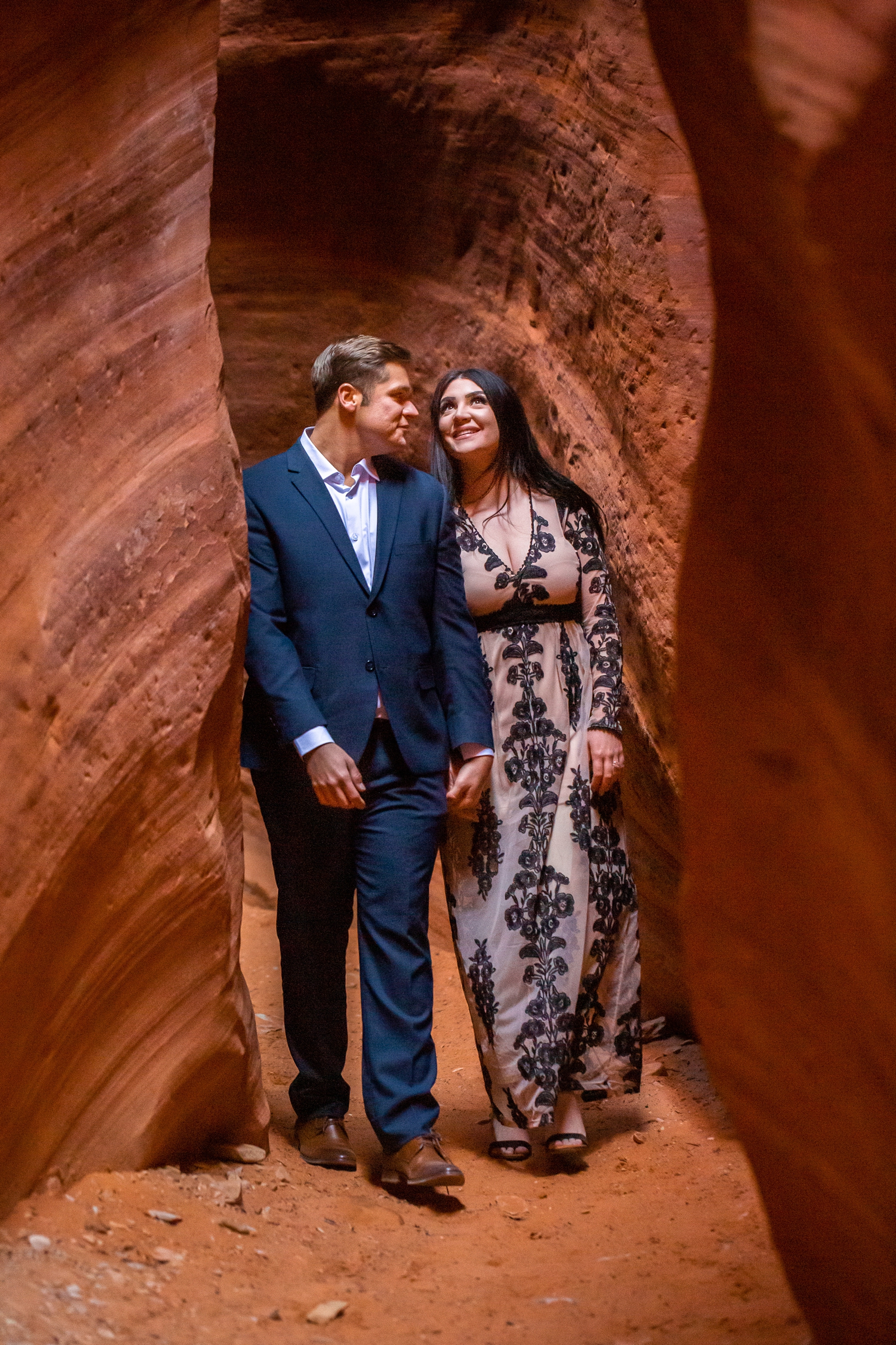 Engaged couple walking through a slot canyon.