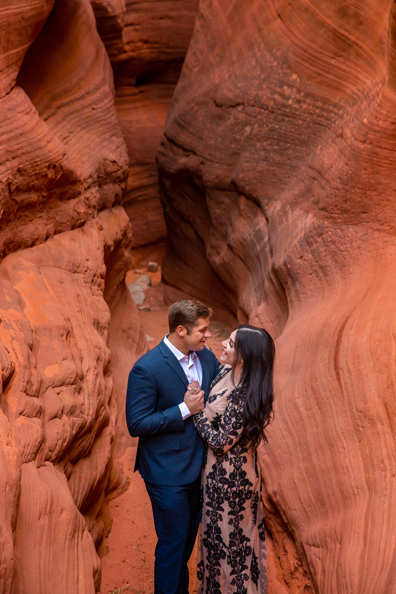 Fun engaged couple dancing in a red rock slot canyon.