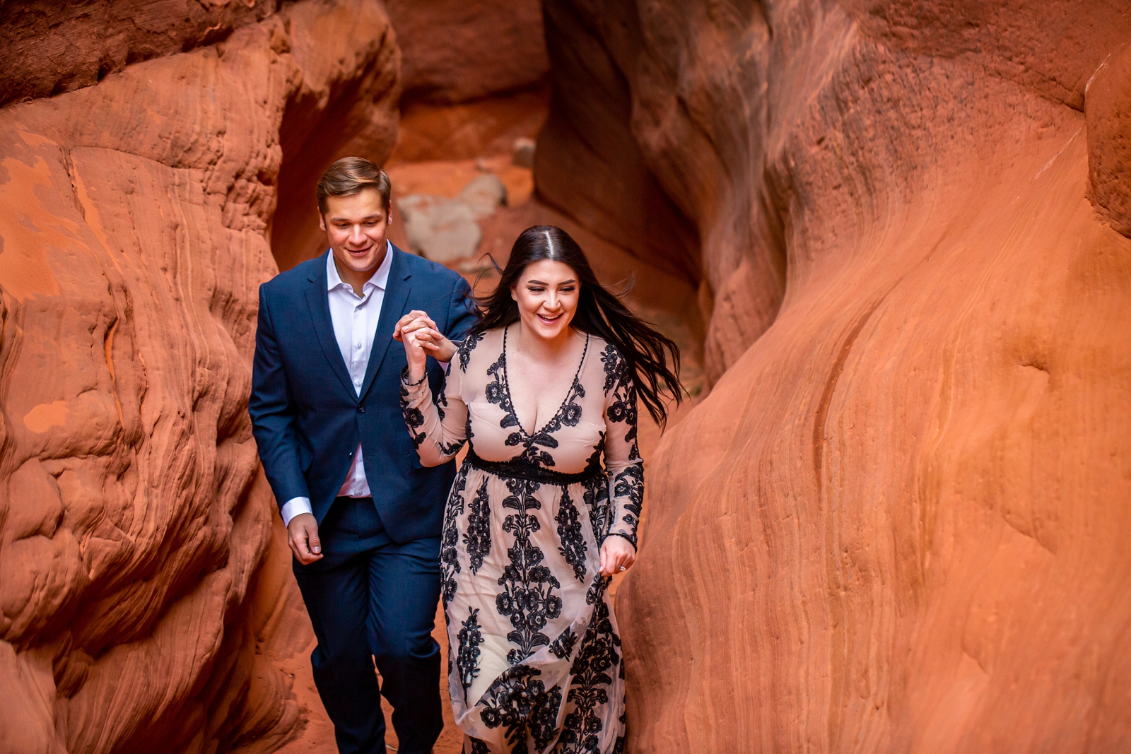 Engaged couple running down a Southern Utah slot canyon.