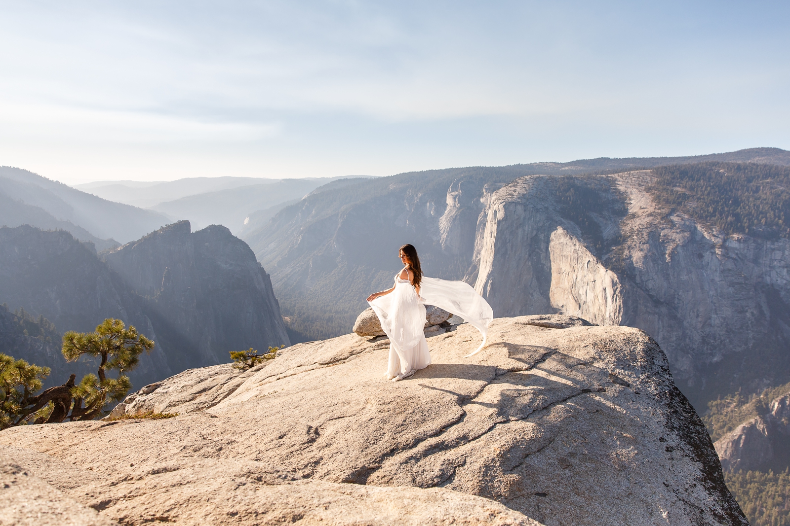 Bride's wedding dress flying in the wind on top of Taft Point.