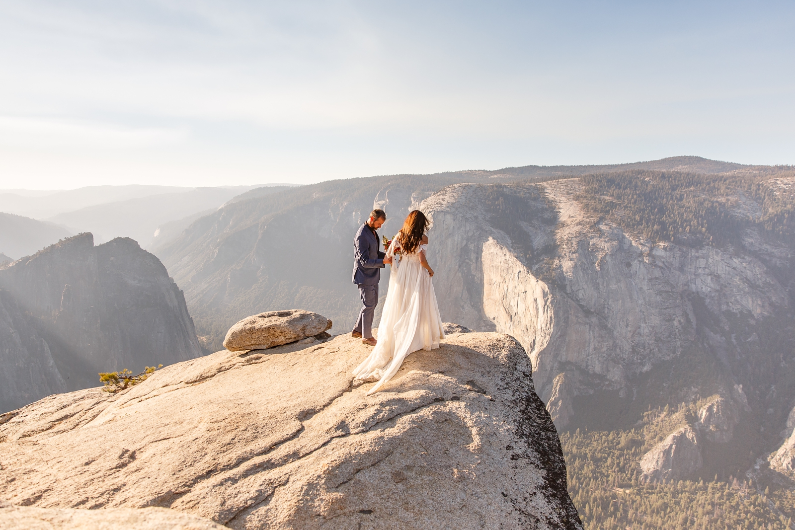 Brave bride and groom walk out to the edge of the cliff at Taft Point Yosemite.