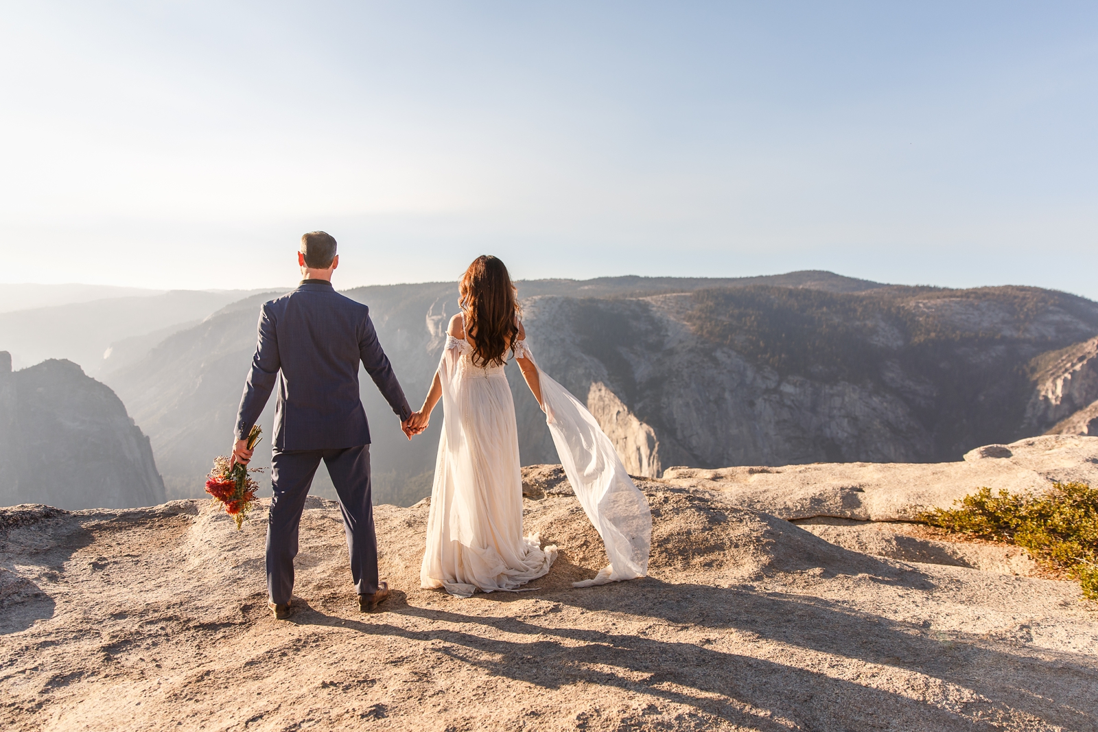 Bride and groom looking over the cliff at Taft Point Yosemite.