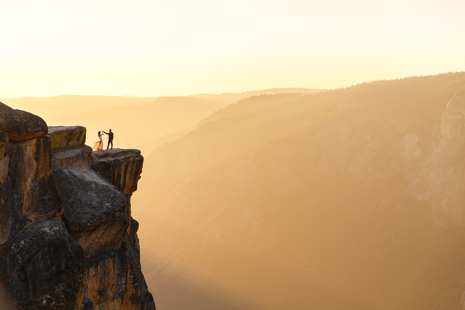 Bride and groom dancing on the edge of a cliff in Yosemite.