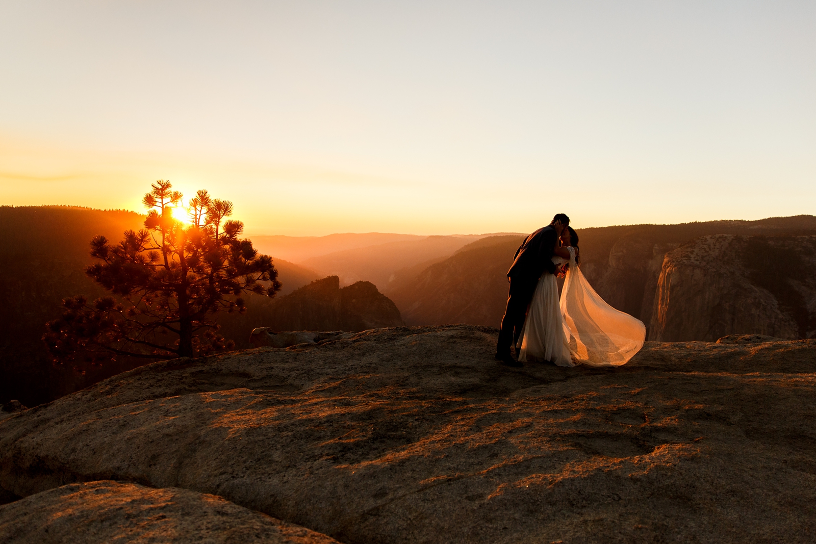 Dreamy bride and groom kiss at sunset in Yosemite.