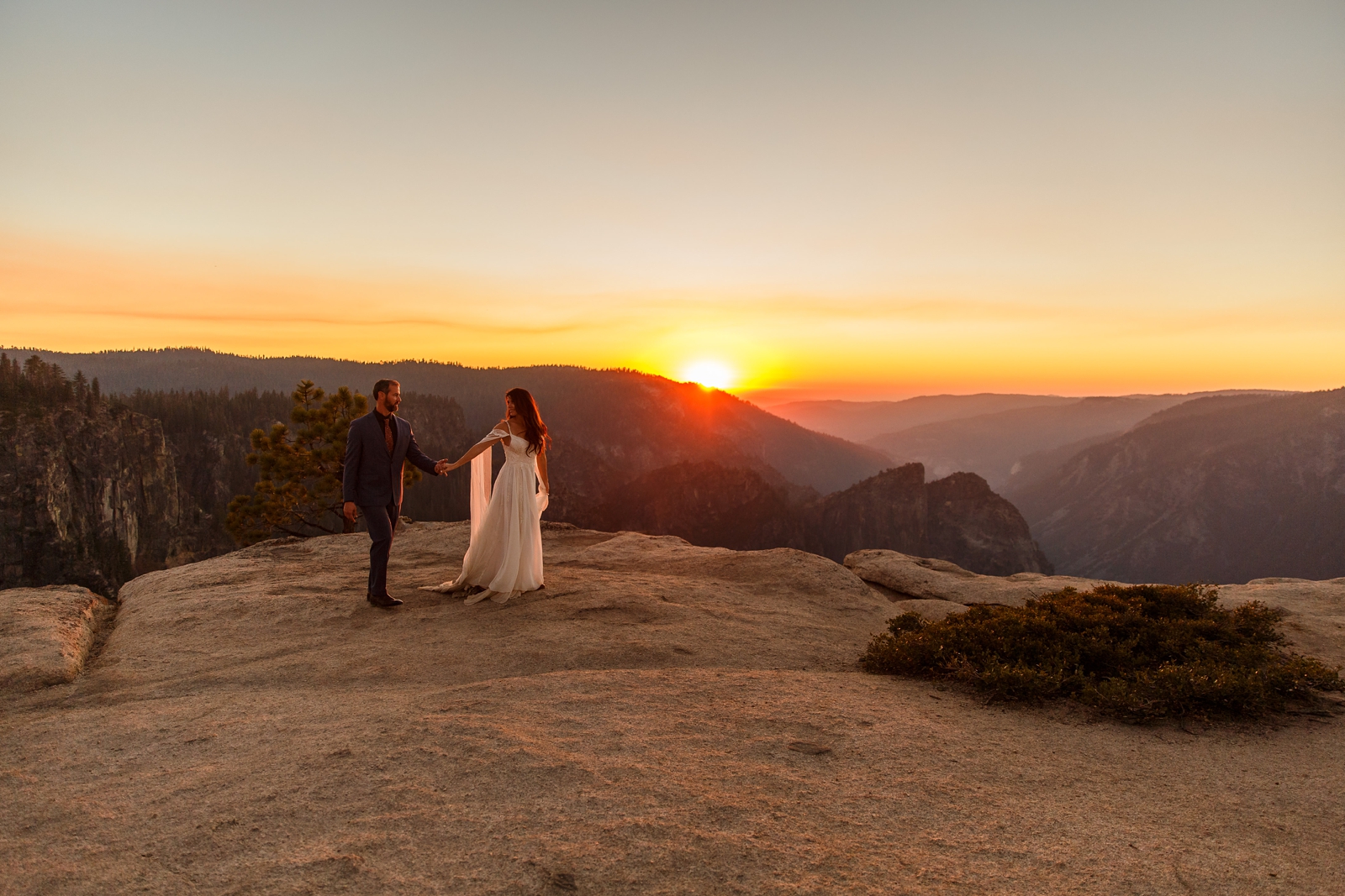 Bride and groom strolling at Taft Point at sunset.