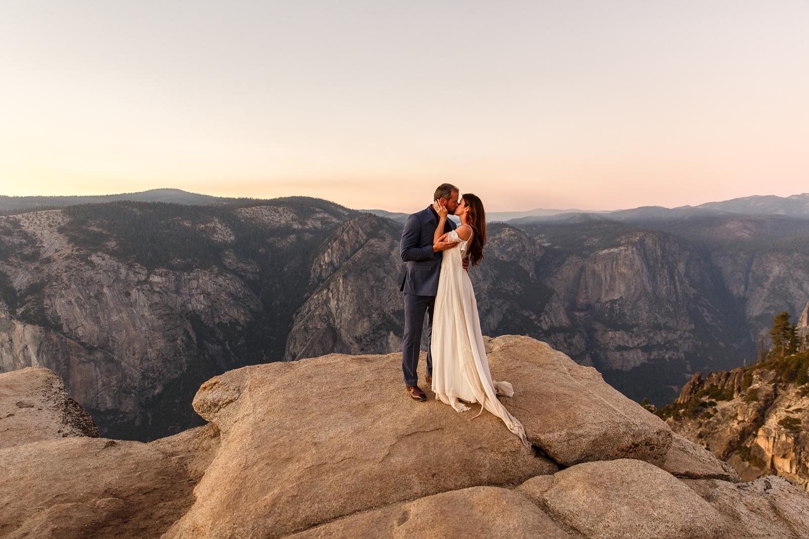 Dreamy married couple kissing at Taft Point in Yosemite NP.
