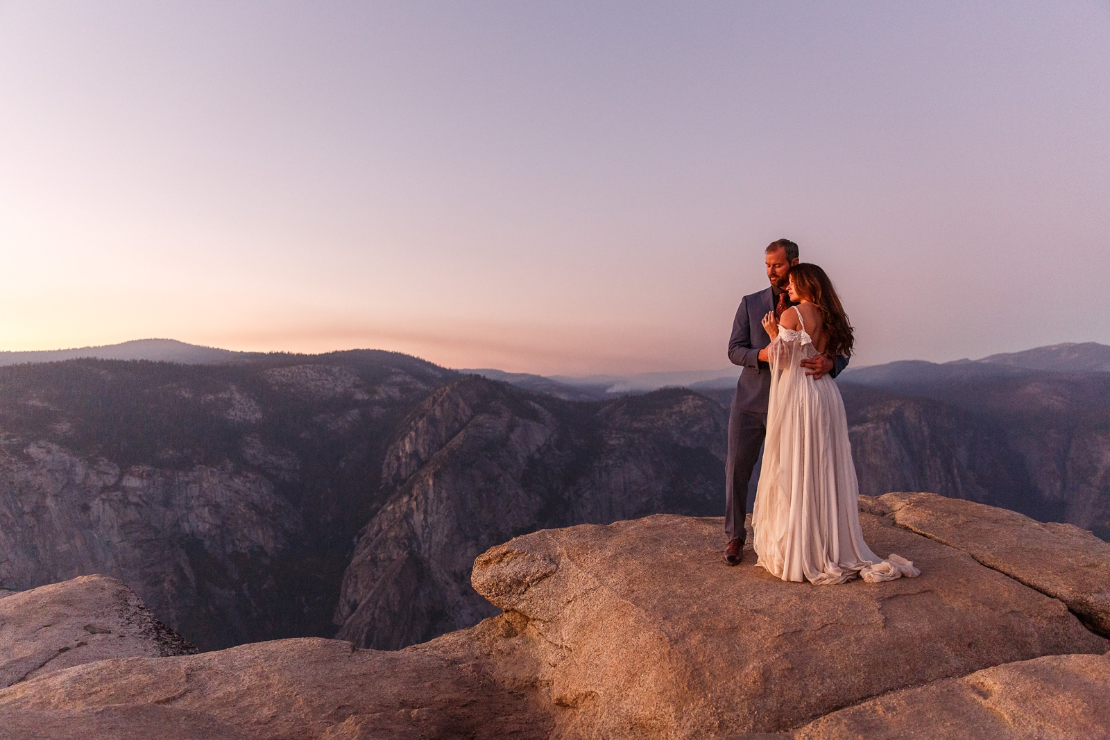 Cuddling eloping couple at pink hour in Yosemite.