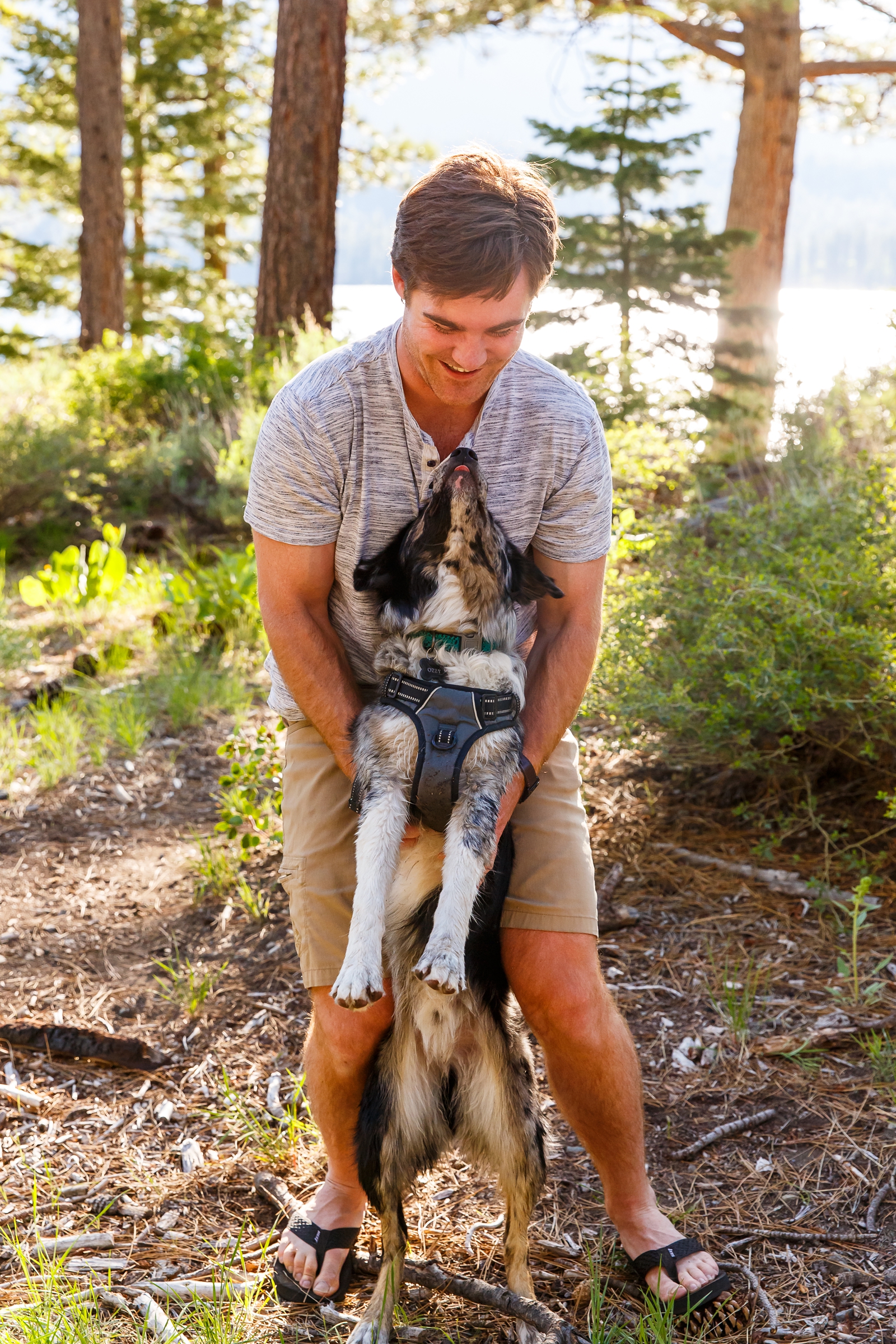 a guy holding his dog by Lake Tahoe