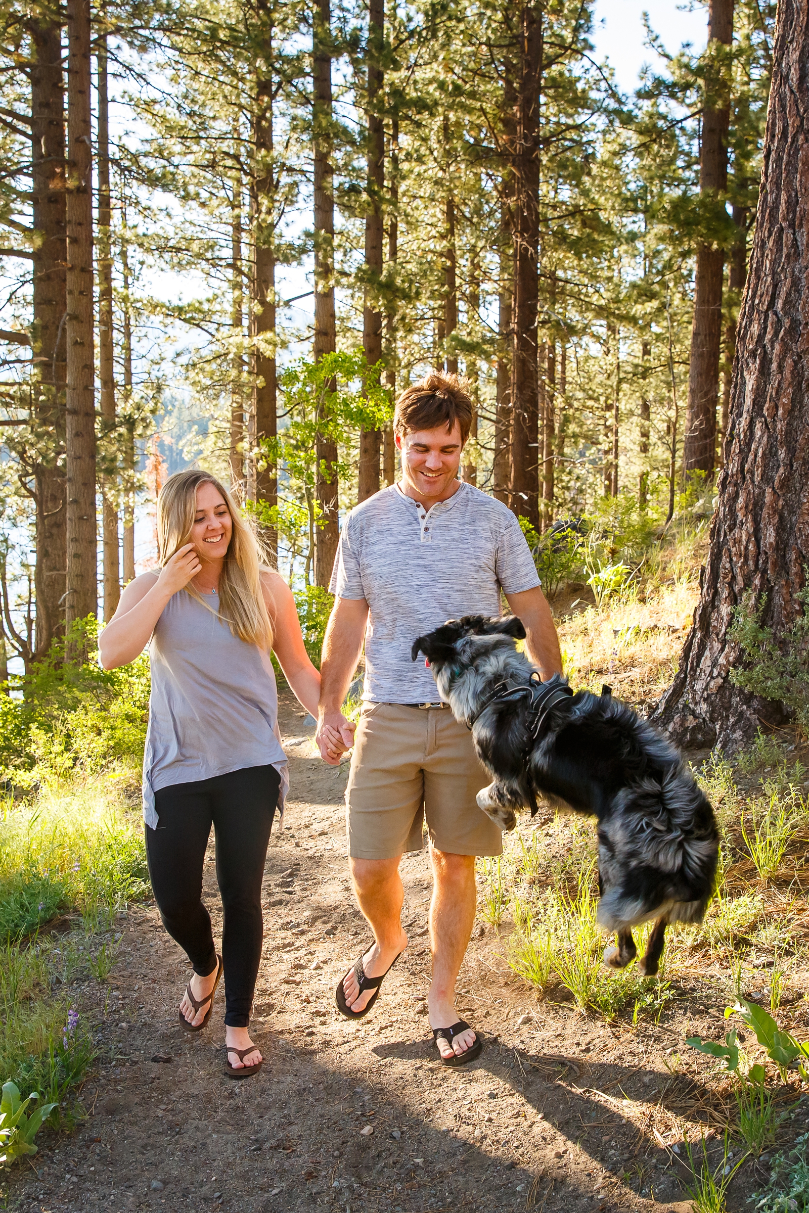 a couple holding hands with their dog running in front of them by Lake Tahoe for their adventure session