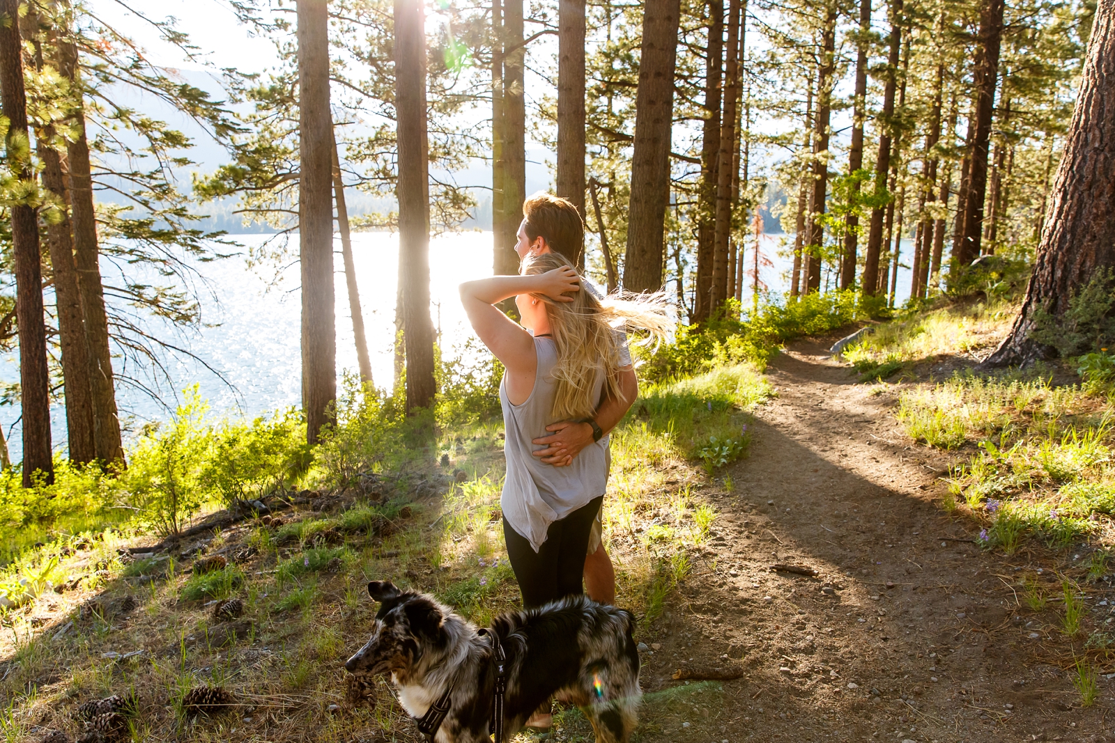 a couple holding hands with their dog running in front of them by Lake Tahoe for their adventure session