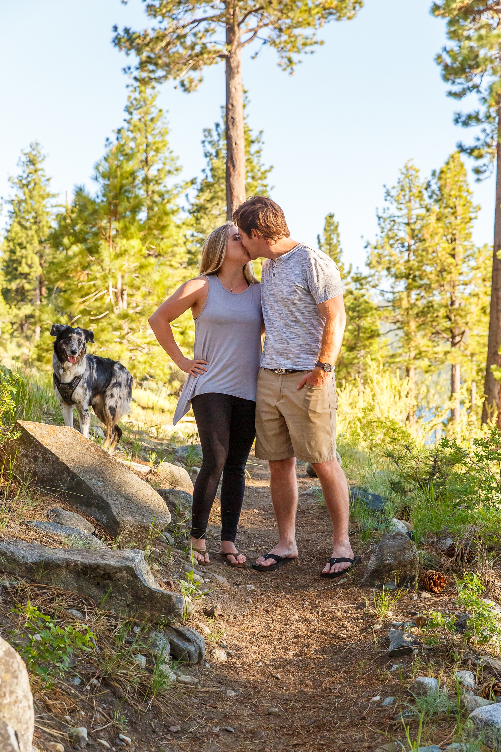 a couple kissing by Lake Tahoe for their adventure session with their dog in the background