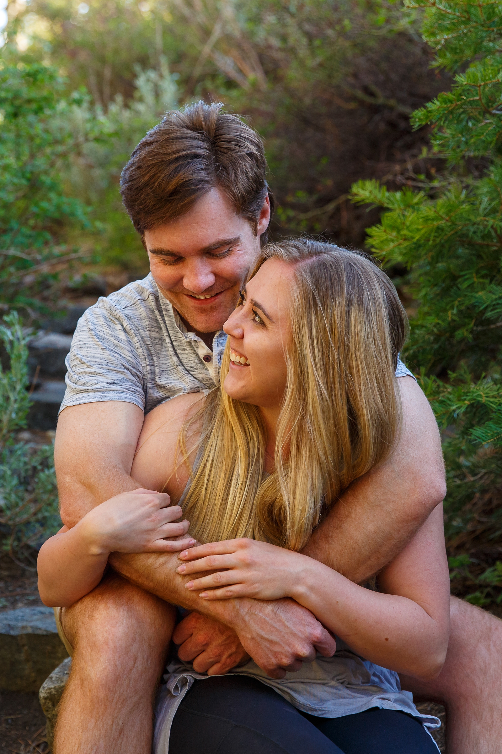 a couple sitting on a rock embracing smiling at each other during their Lake Tahoe area adventure session