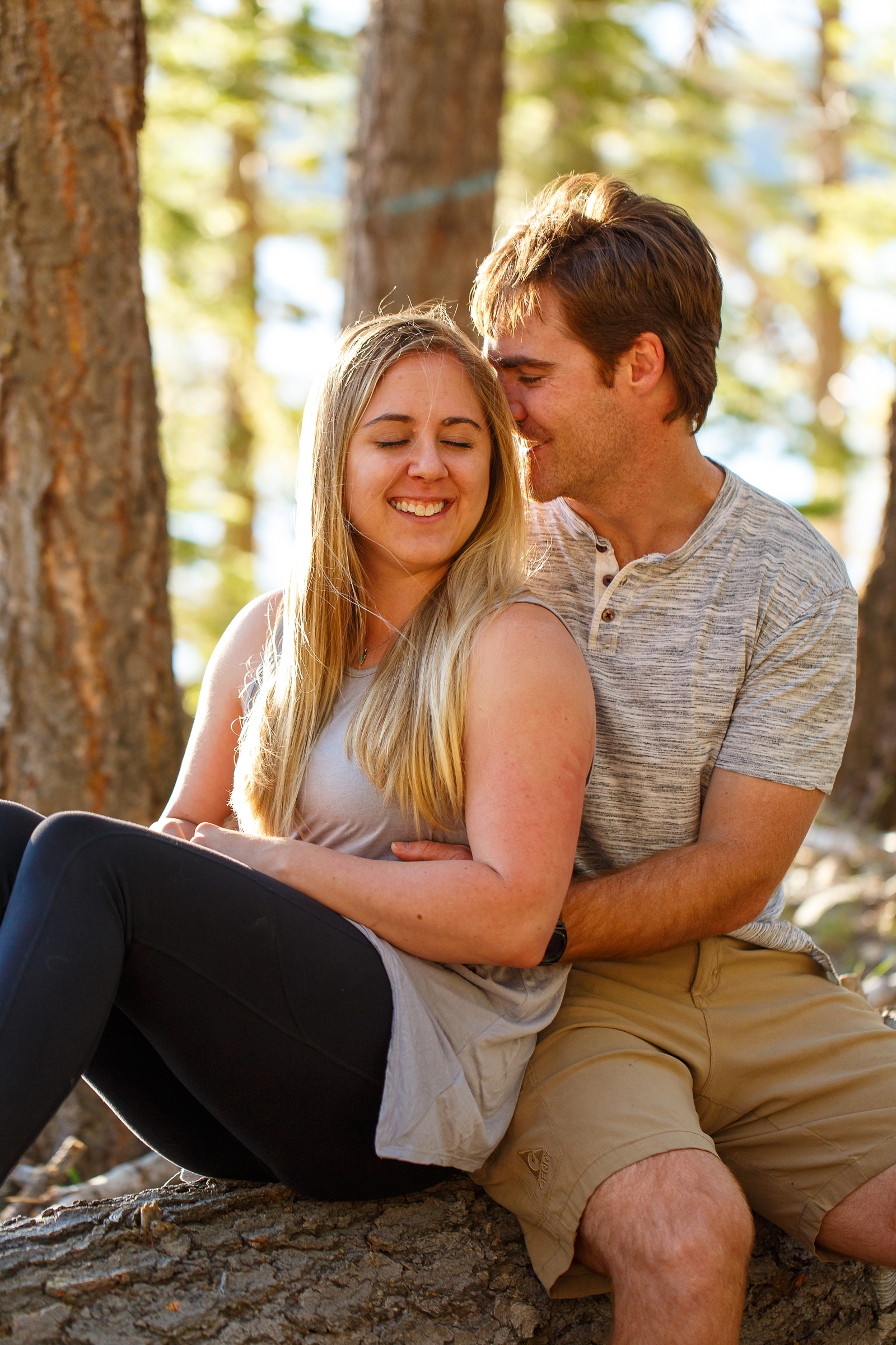 a couple sitting on a fallen branch embracing during their Tahoe area adventure session
