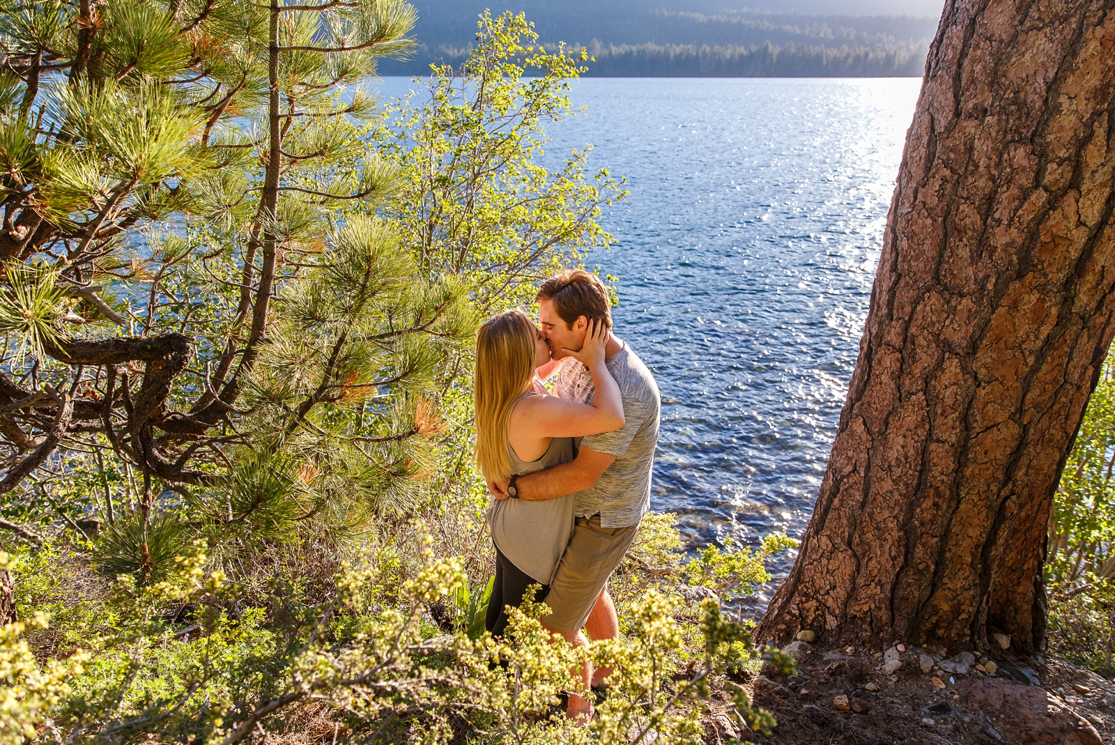 a couple kissing in front of Lake Tahoe during their adventure session in the Tahoe area