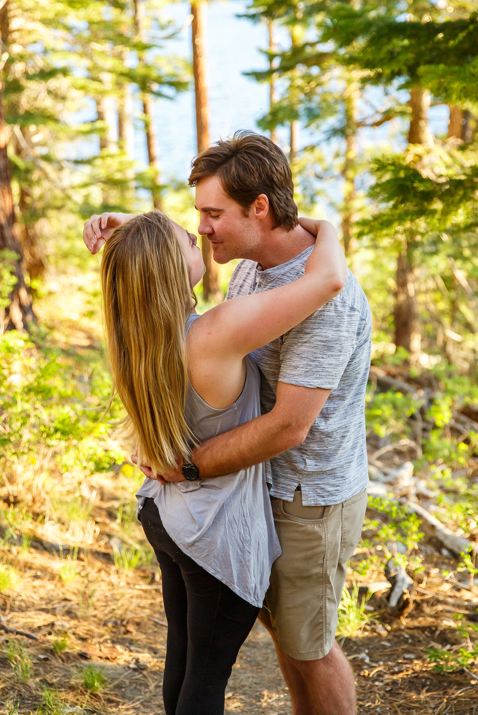 a couple almost kissing with Lake Tahoe and pine trees in the background during their adventure session in the Tahoe area