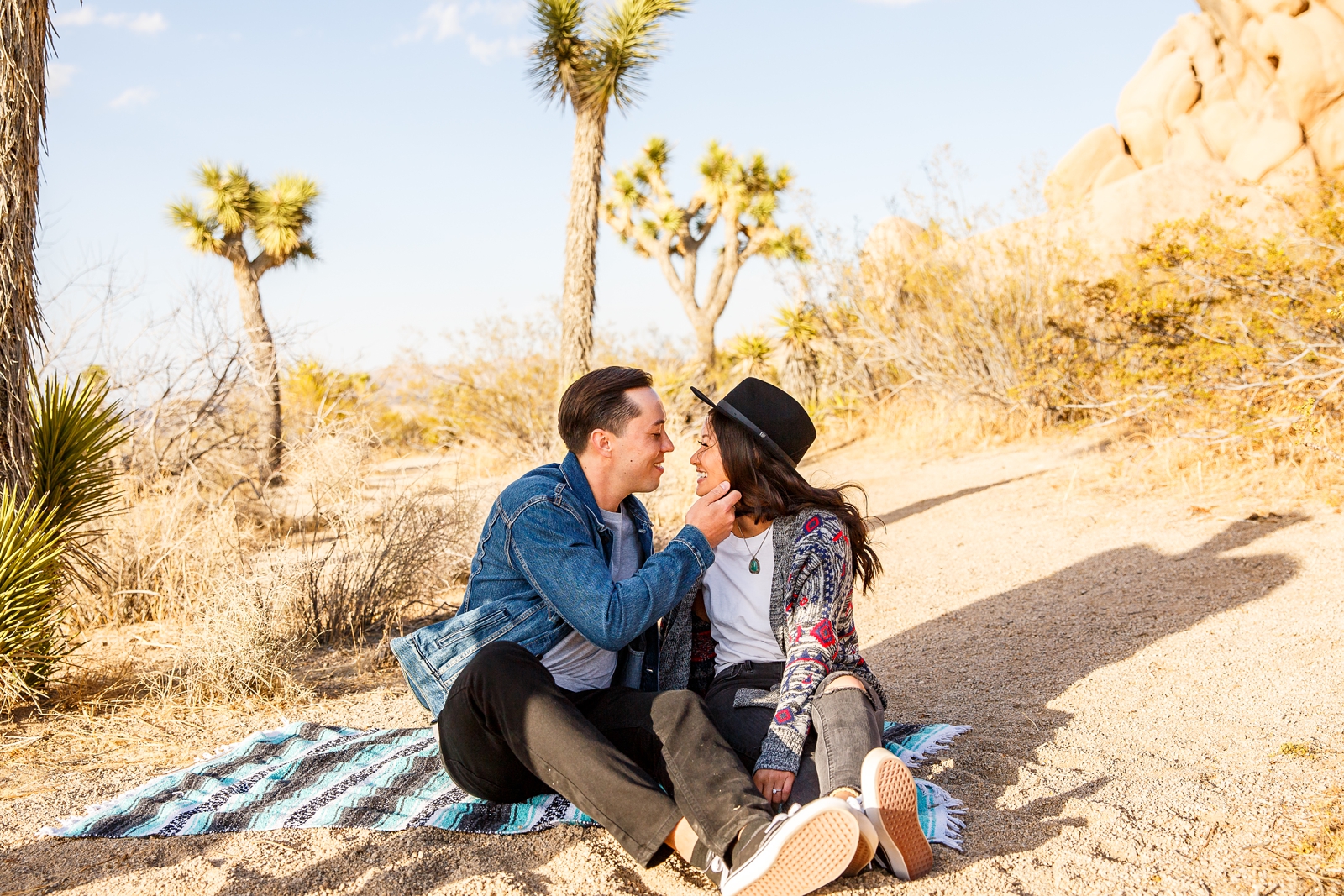 Adorable engaged couple cuddling on a blanket in Joshua Tree NP.