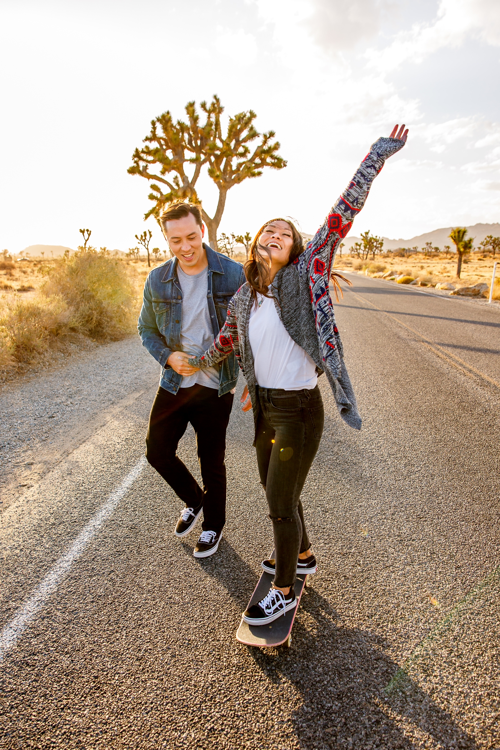 Carefree engaged couple skateboarding at golden hour in Joshua Tree. 