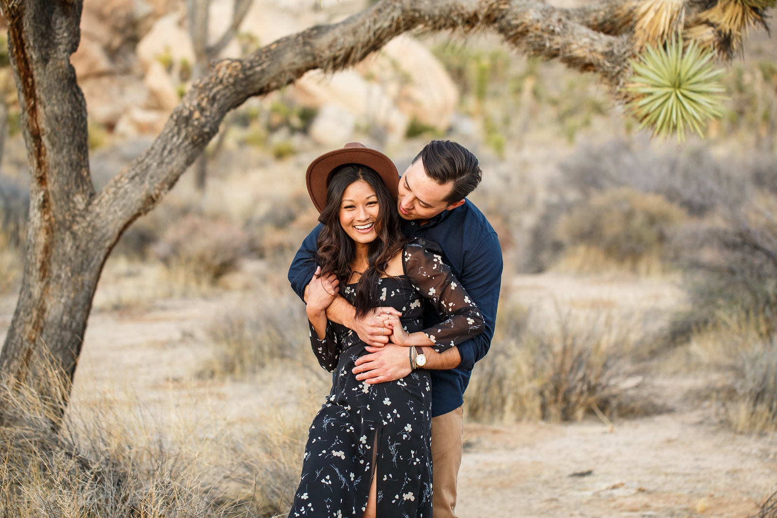 Adorable engaged couple cuddling in Joshua Tree National Park.