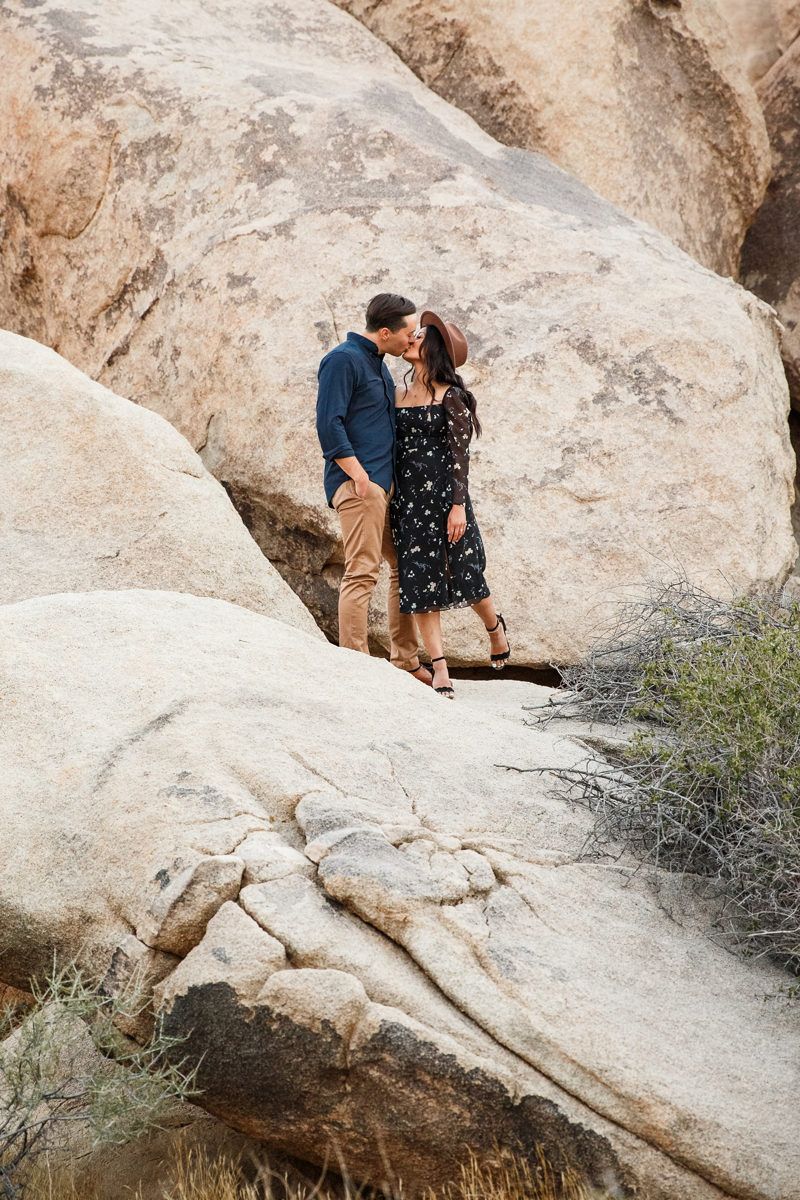 Engaged couple kissing on rocks in Joshua Tree.
