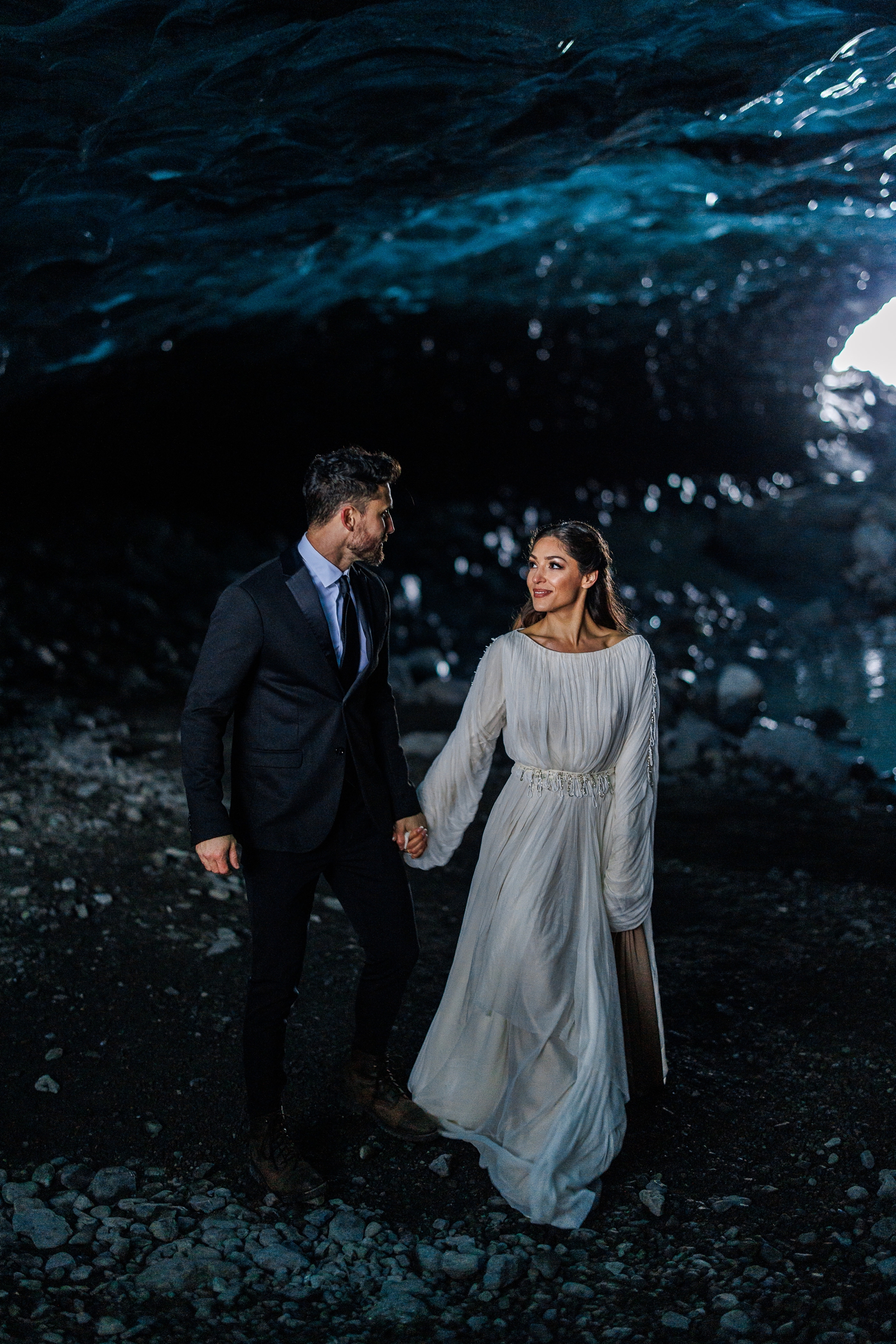 A couple walking hand in hand through a wintery ice cave during their Iceland elopement. 