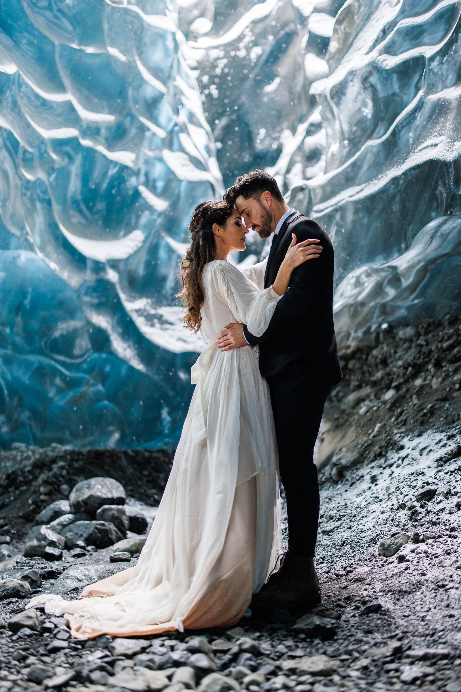 An eloping couple gently press their temples together while in a glacier cave in Iceland.