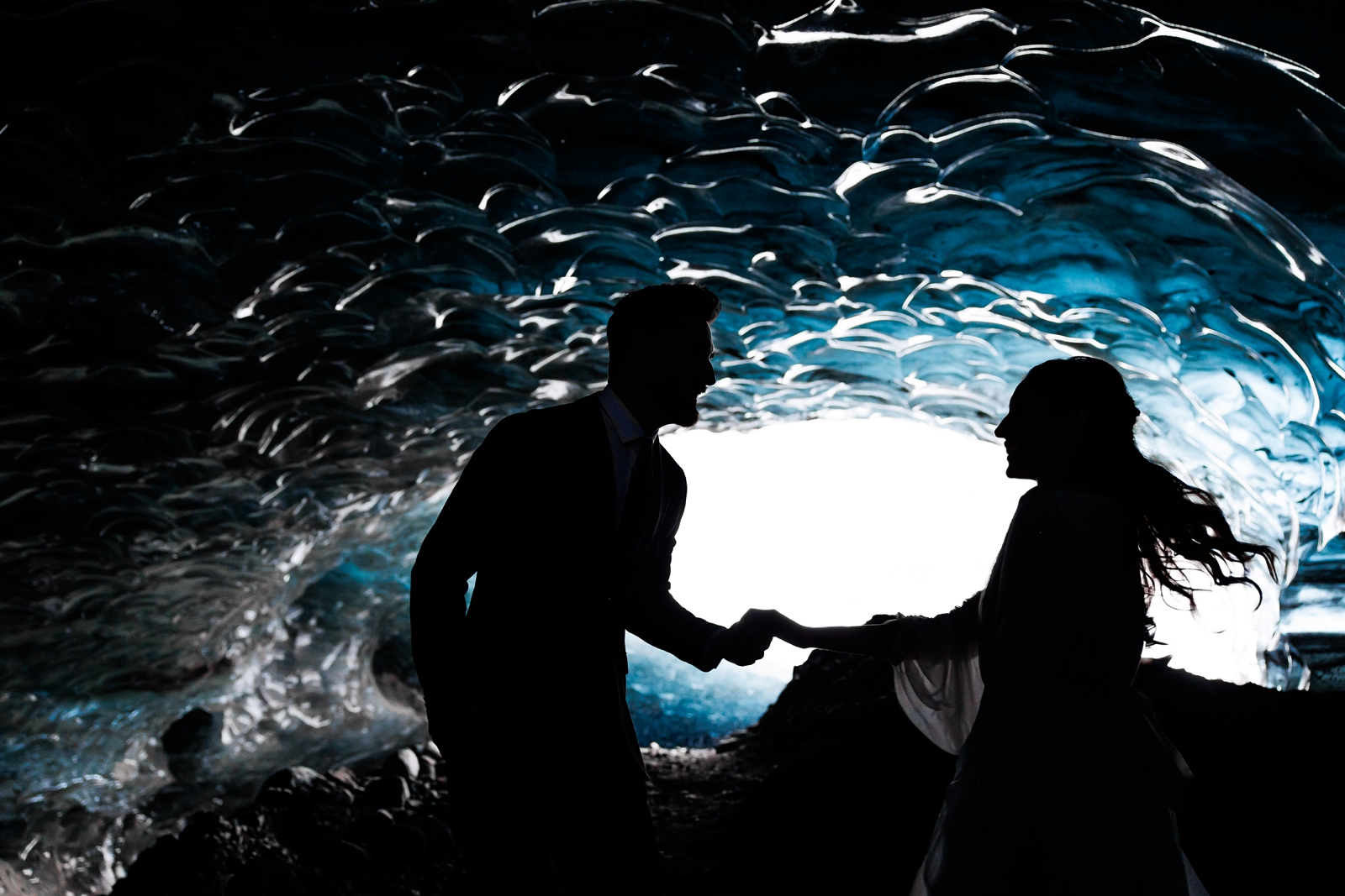 A couple runs through a glacier ice cave on their elopement wedding day in Iceland.
