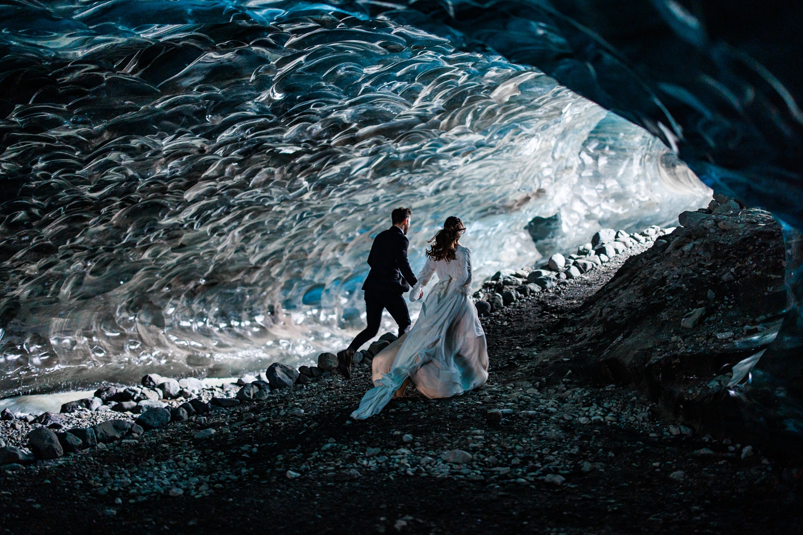 A bride and groom run through the magnificent halls of this Iceland ice cave.