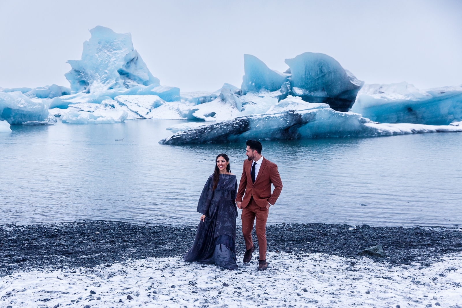 An eloping couple walks along the frigid glacier lagoon in Southern Iceland.