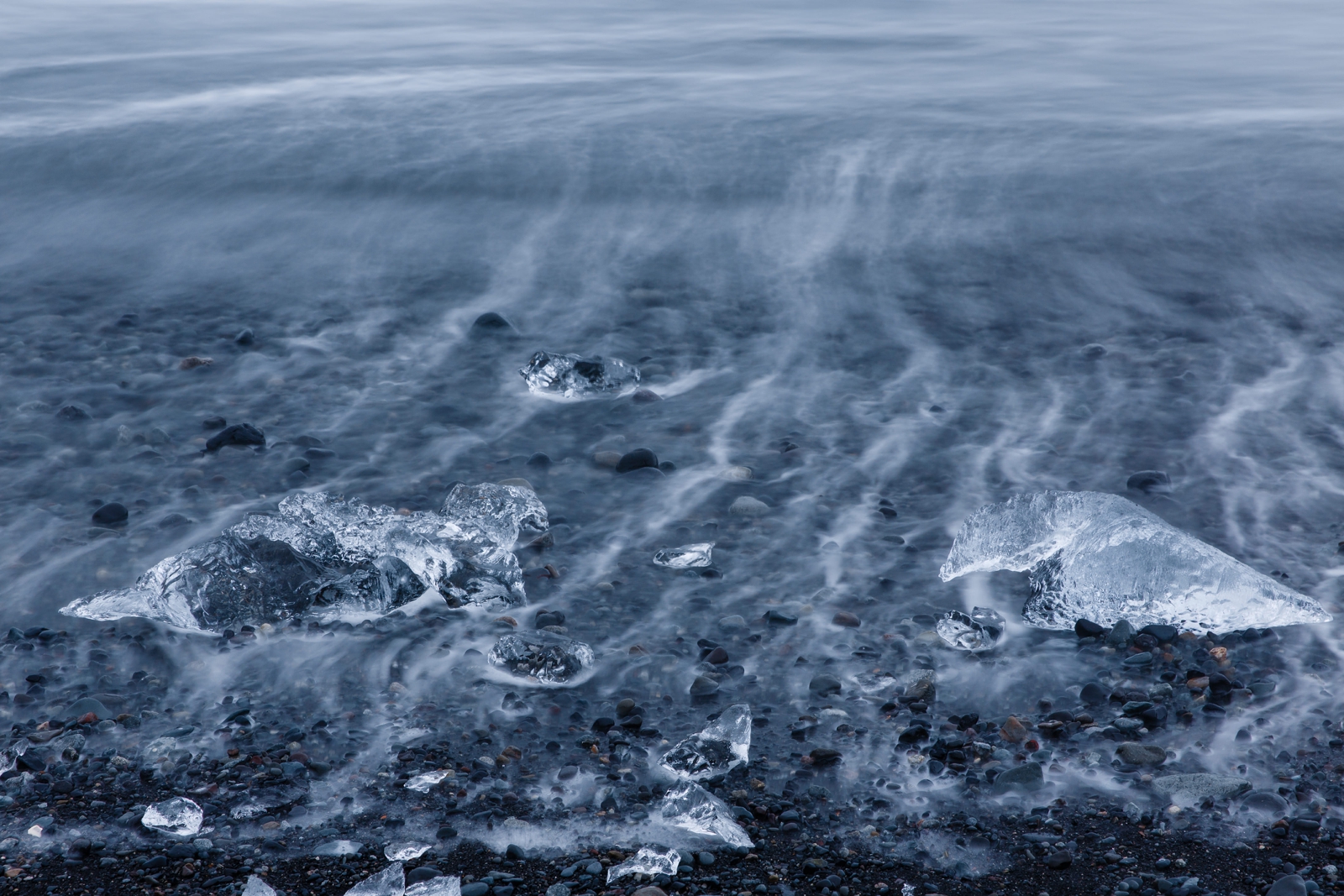 Waves streaking through ice diamonds on a black sand beach in Iceland.