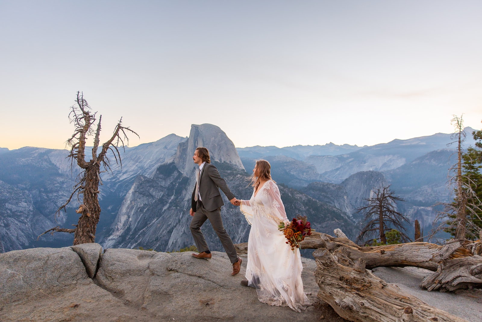 Eloping bride and groom hiking by Half Dome in Yosemite.