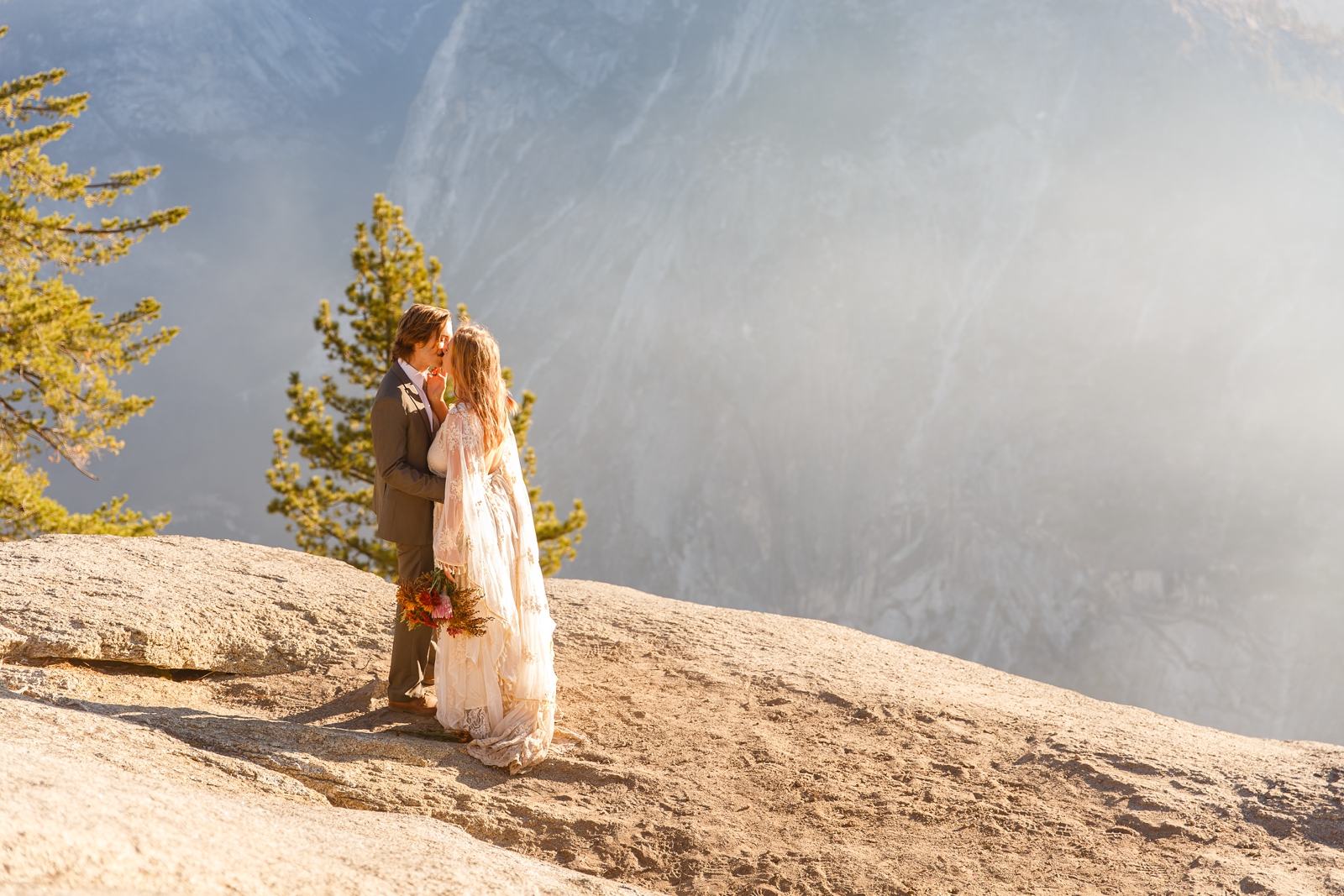 Eloping couple kisses on the cliff in Yosemite.