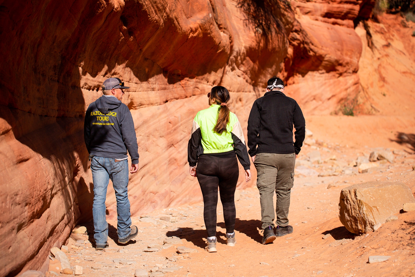 A couple and tour guide looking at rock during their Fun Utah slot canyon adventure