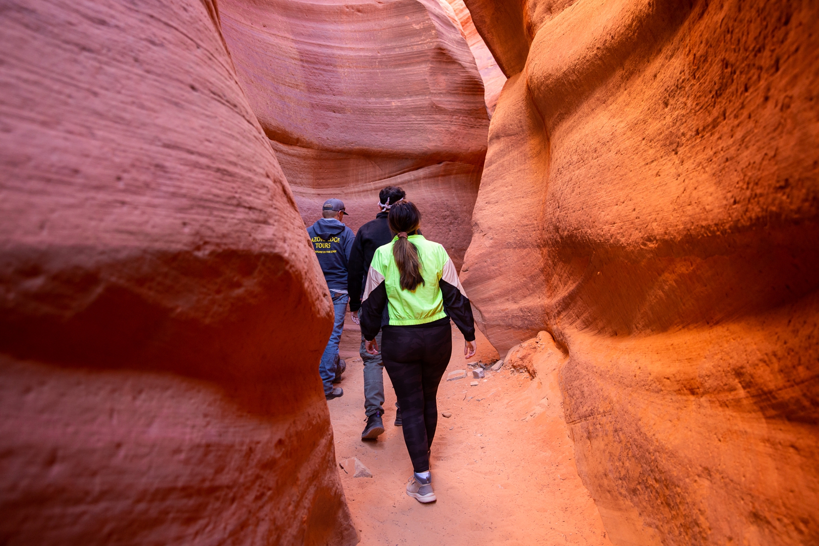 A couple and tour guide walking through the Utah slot canyon during their hiking adventure