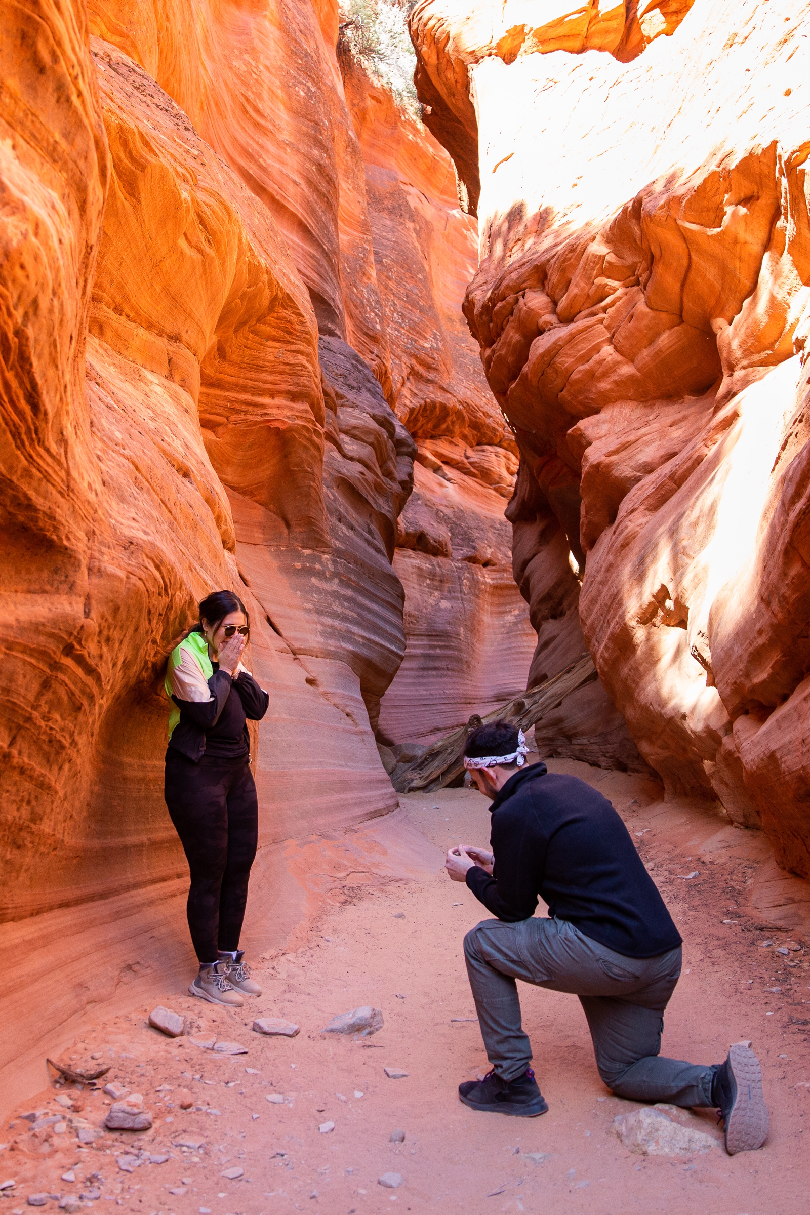 A guy down on his knee proposing to his girlfriend in the middle of the Utah slot canyon during their adventurous hike