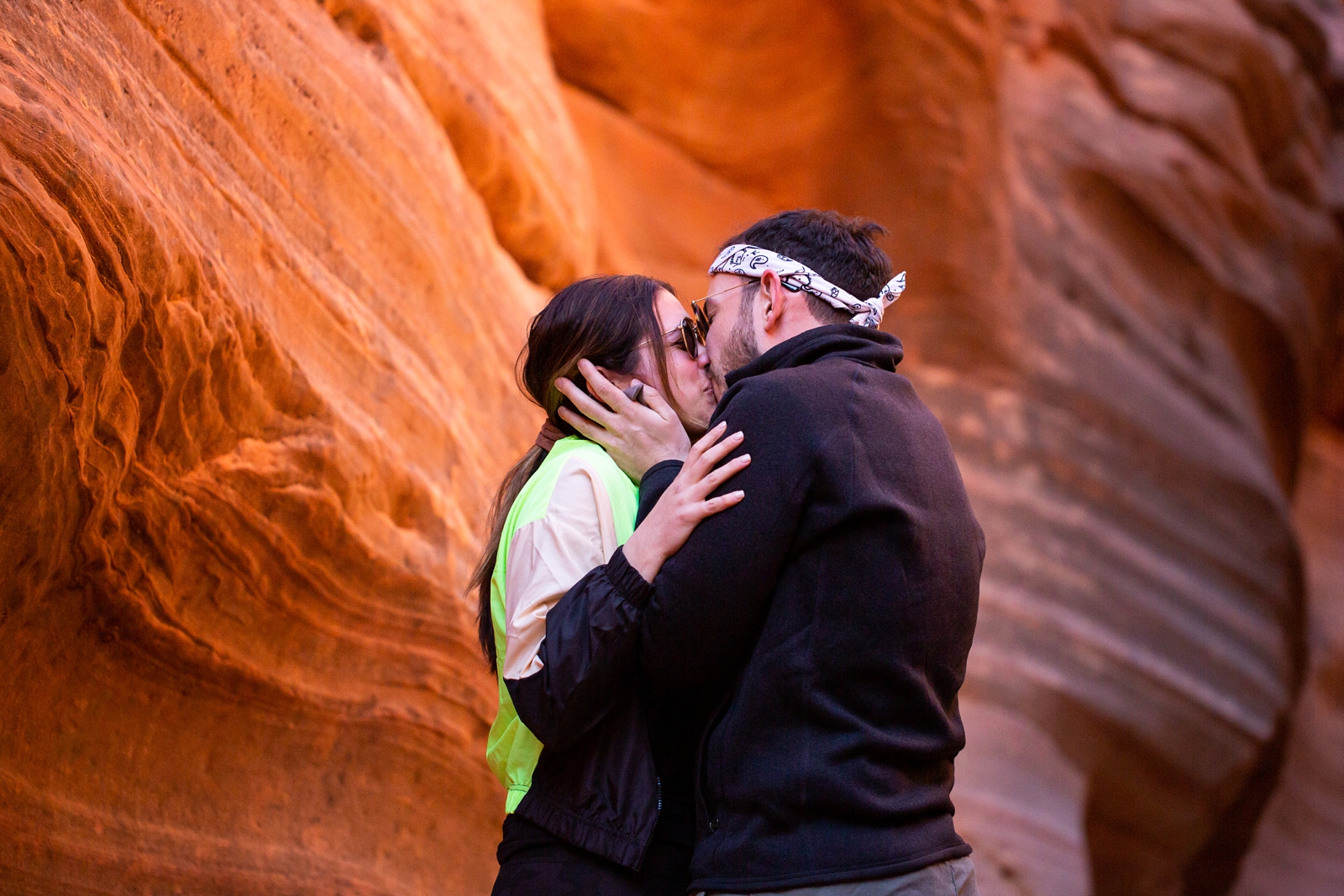 A newly engaged couple kissing after their surprise proposal in the Utah slot canyon