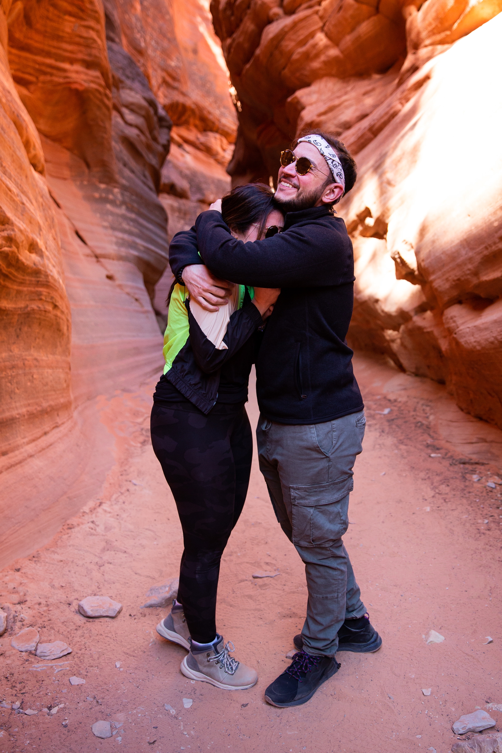 a newly engaged couple embracing after their surprise proposal in the Utah slot canyon during the adventurous hike