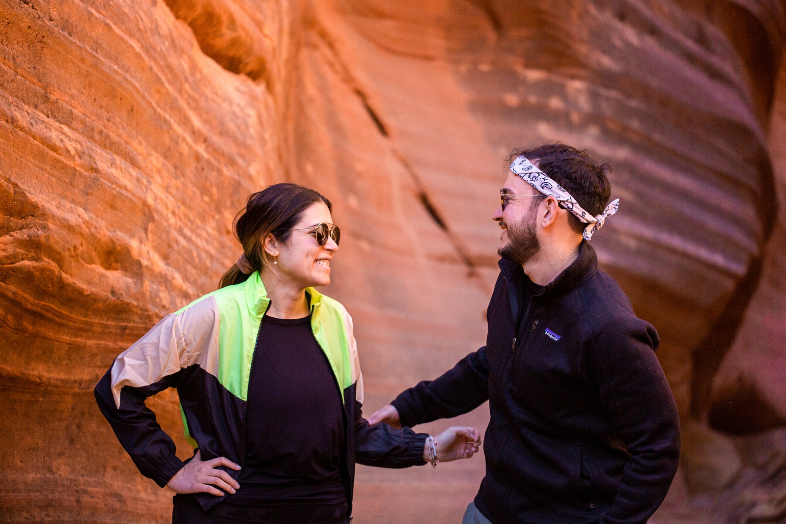 a newly engaged couple posing and smiling at each other for a picture in the Utah Slot Canyon during their adventurous hike