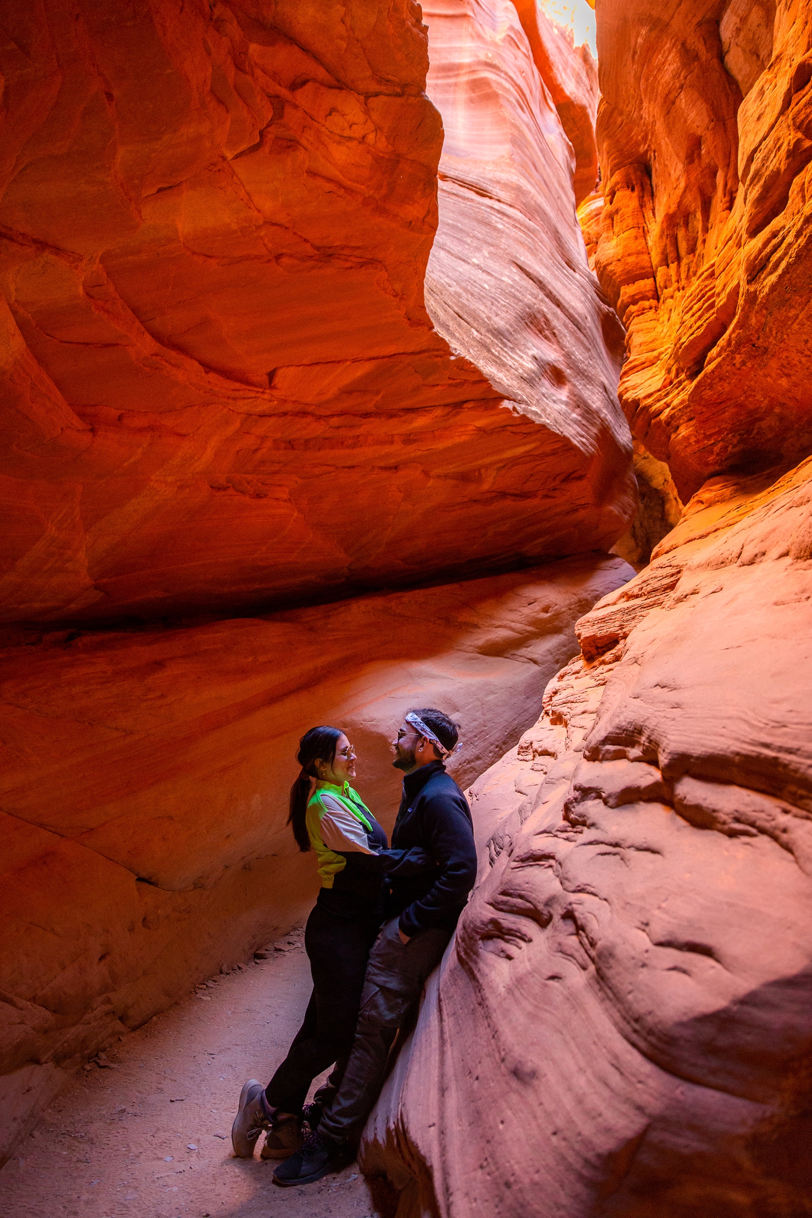 a newly engaged couple posing and smiling at each other for a picture in the Utah Slot Canyon during their adventurous hike